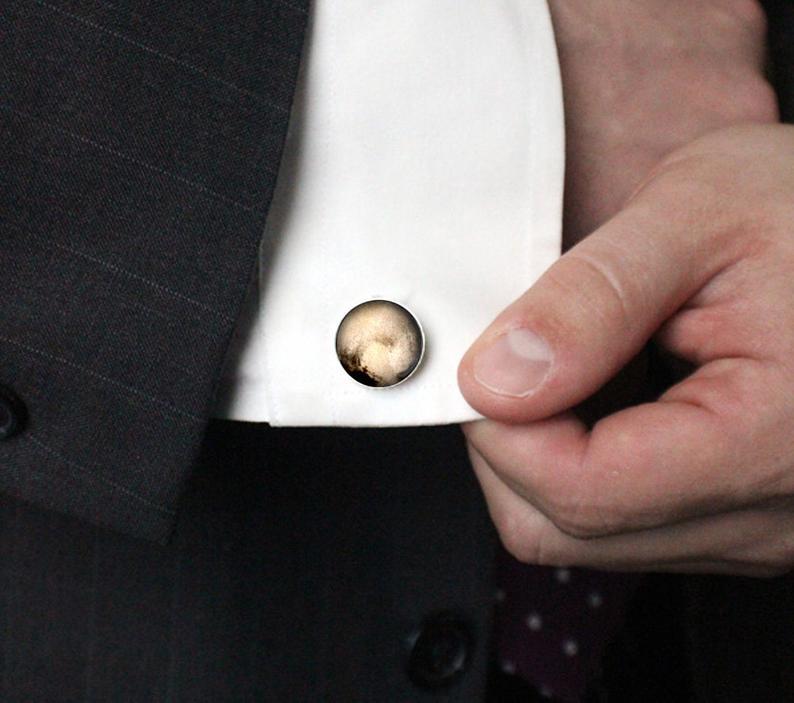 A pair of antique bronze and silver tone cufflinks featuring detailed images of Pluto and its moon Charon, handcrafted from rhodium plated brass and glass.