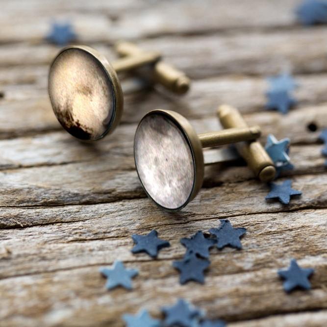 A pair of antique bronze and silver tone cufflinks featuring detailed images of Pluto and its moon Charon, handcrafted from rhodium plated brass and glass.