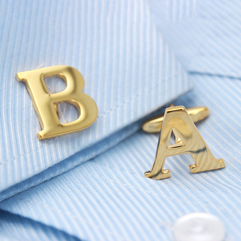 A pair of elegant golden cufflinks featuring capitalized alphabets, beautifully crafted from brass and gold plated, presented in a stylish gift box.