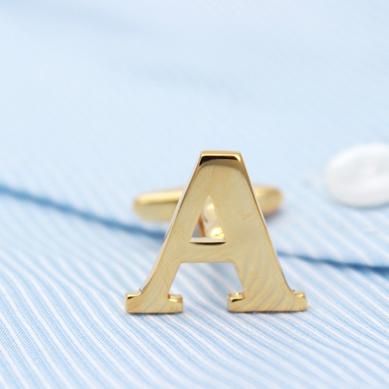 A pair of elegant golden cufflinks featuring capitalized alphabets, beautifully crafted from brass and gold plated, presented in a stylish gift box.