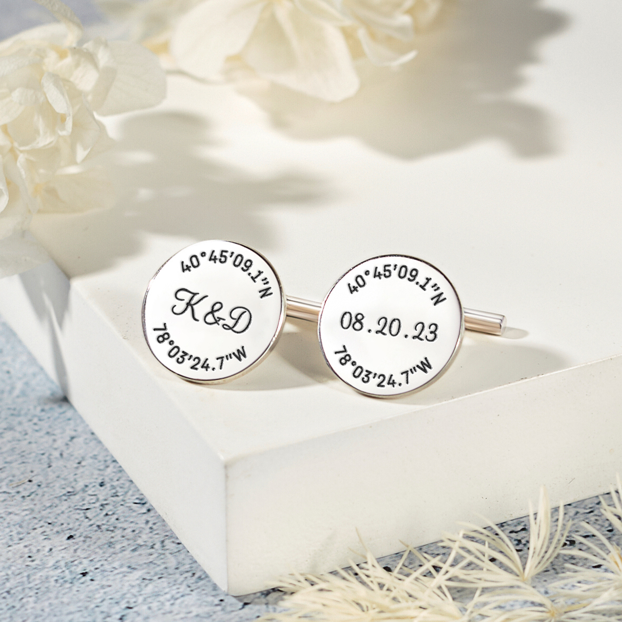 A pair of personalized groom cufflinks made from solid 925 sterling silver, engraved with custom coordinates and initials, elegantly displayed in a gift box.