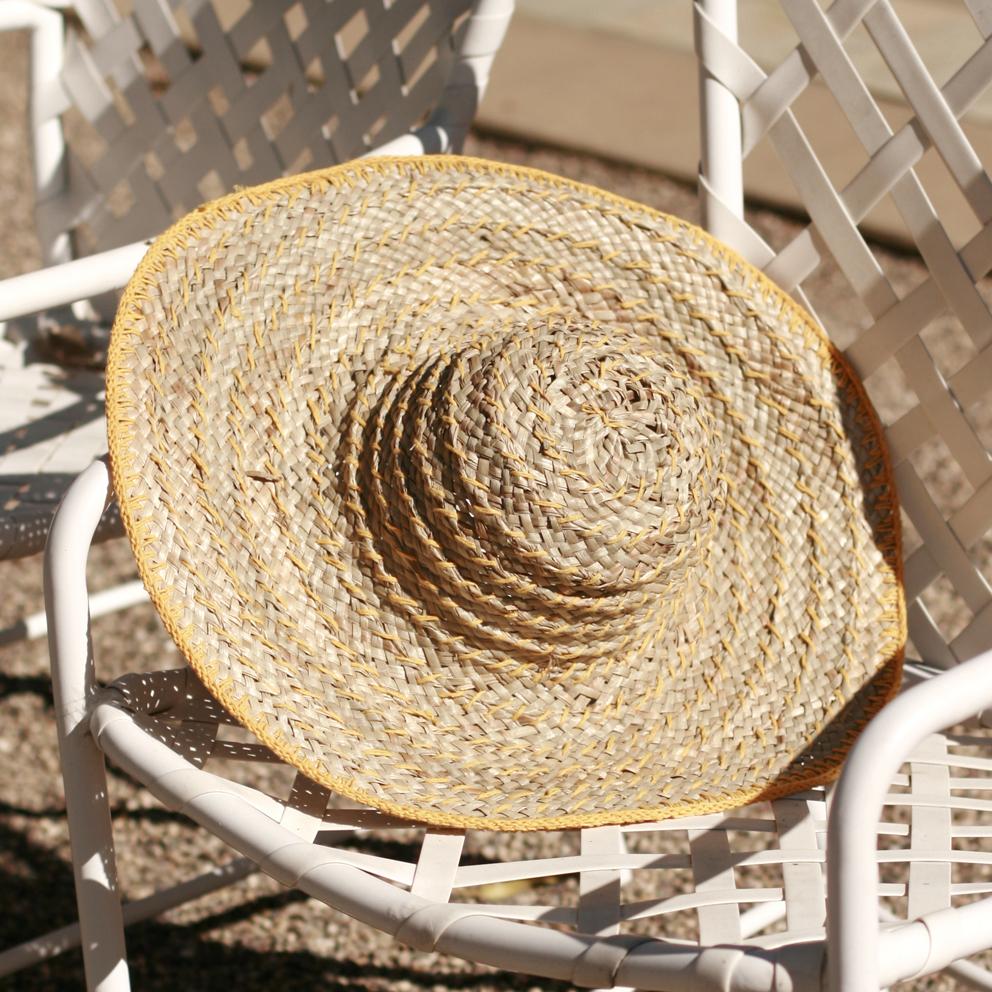 Balinese Pecatu Wide Round Straw Hat in Butter Yellow, handmade from seagrass with a flexible structure and dyed cotton strings.