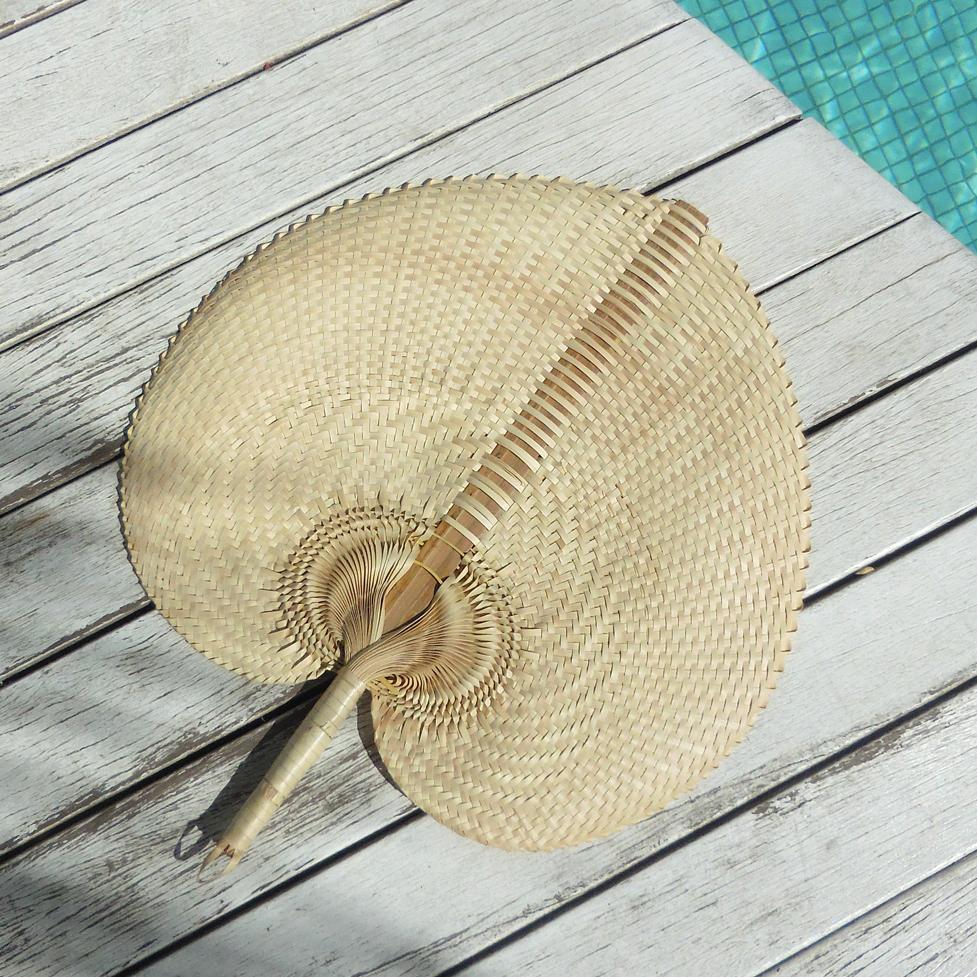 A beautifully handwoven Balinese fan made from Lontar Palm straws, showcasing intricate patterns and available in three sizes.