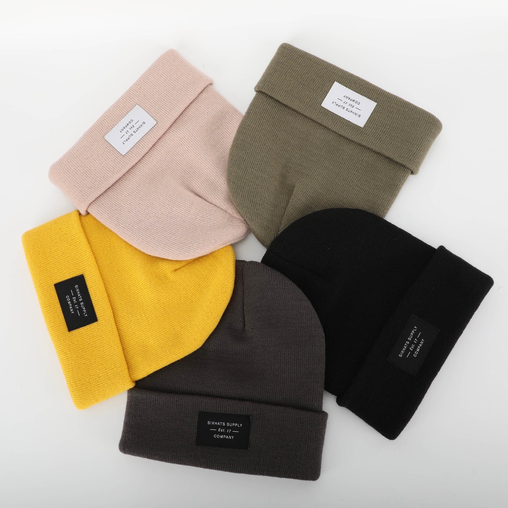 A soft beige folding beanie displayed on a neutral background, showcasing its stylish design and woven label.