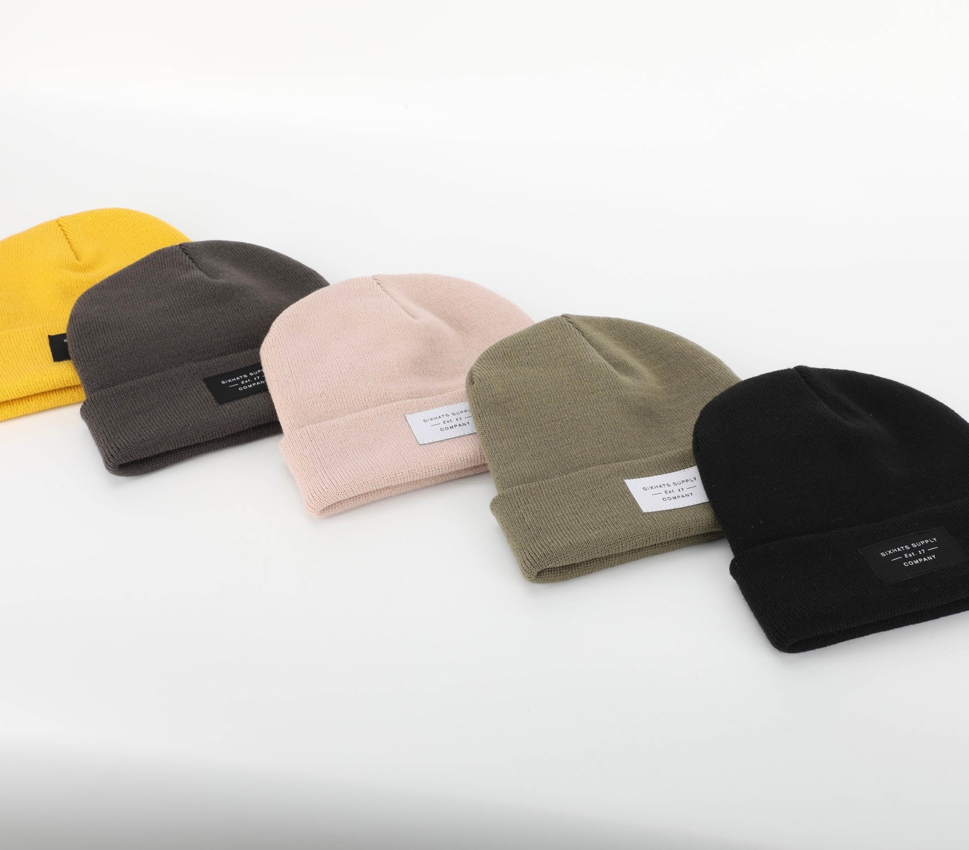 A soft beige folding beanie displayed on a neutral background, showcasing its stylish design and woven label.