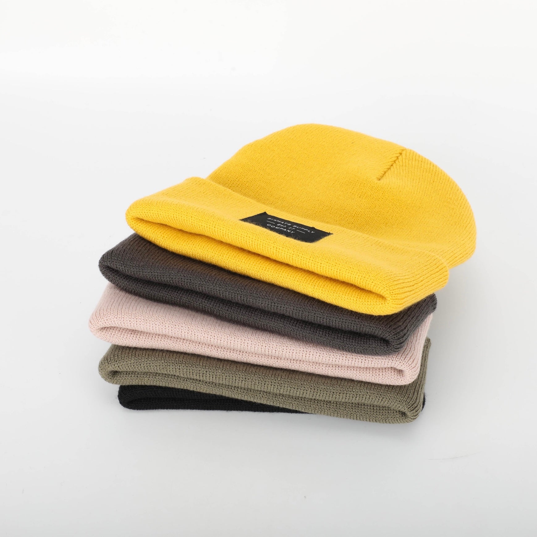 A soft beige folding beanie displayed on a neutral background, showcasing its stylish design and woven label.