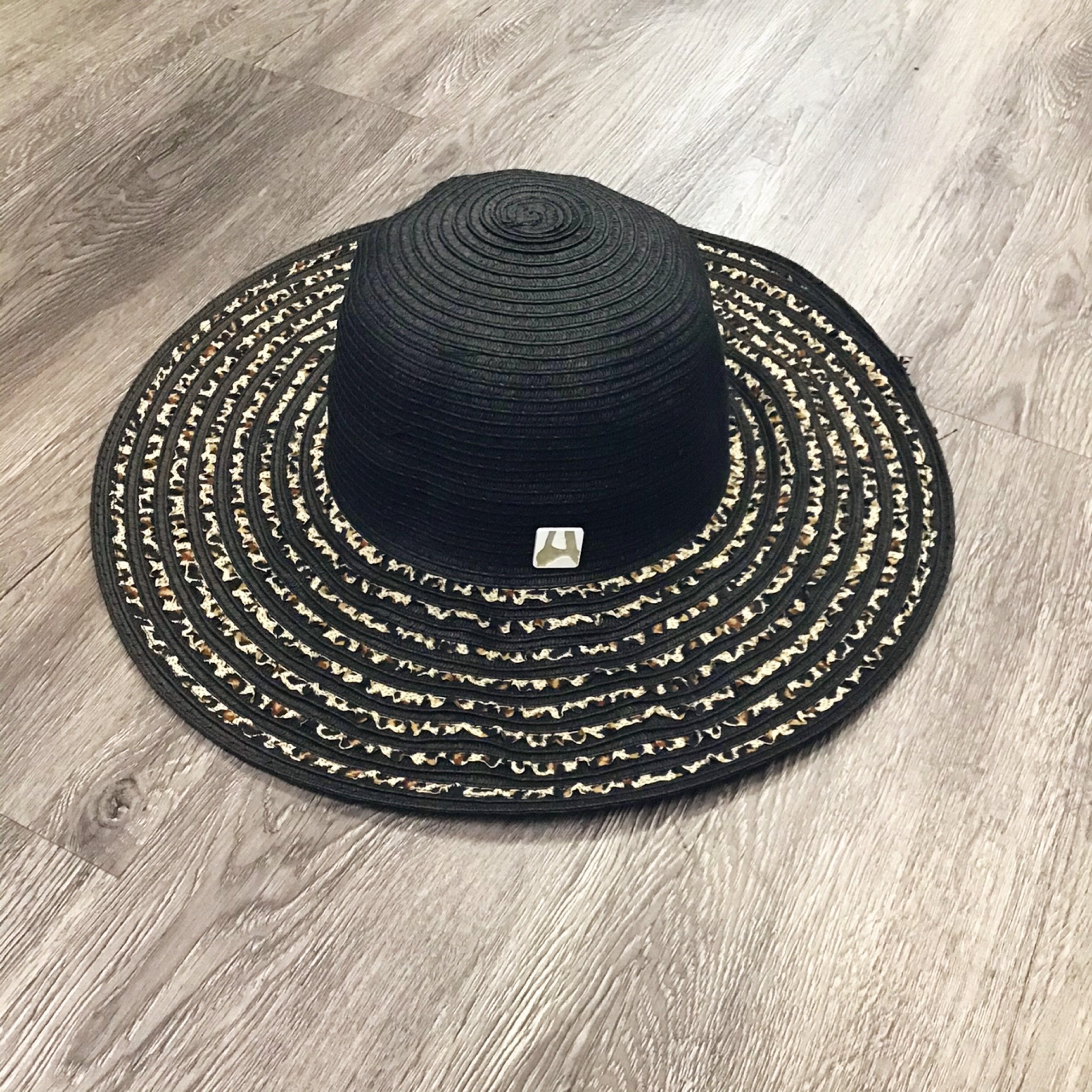 A stylish black straw beach hat with an animal print ribbon, perfect for sun protection and summer outings.