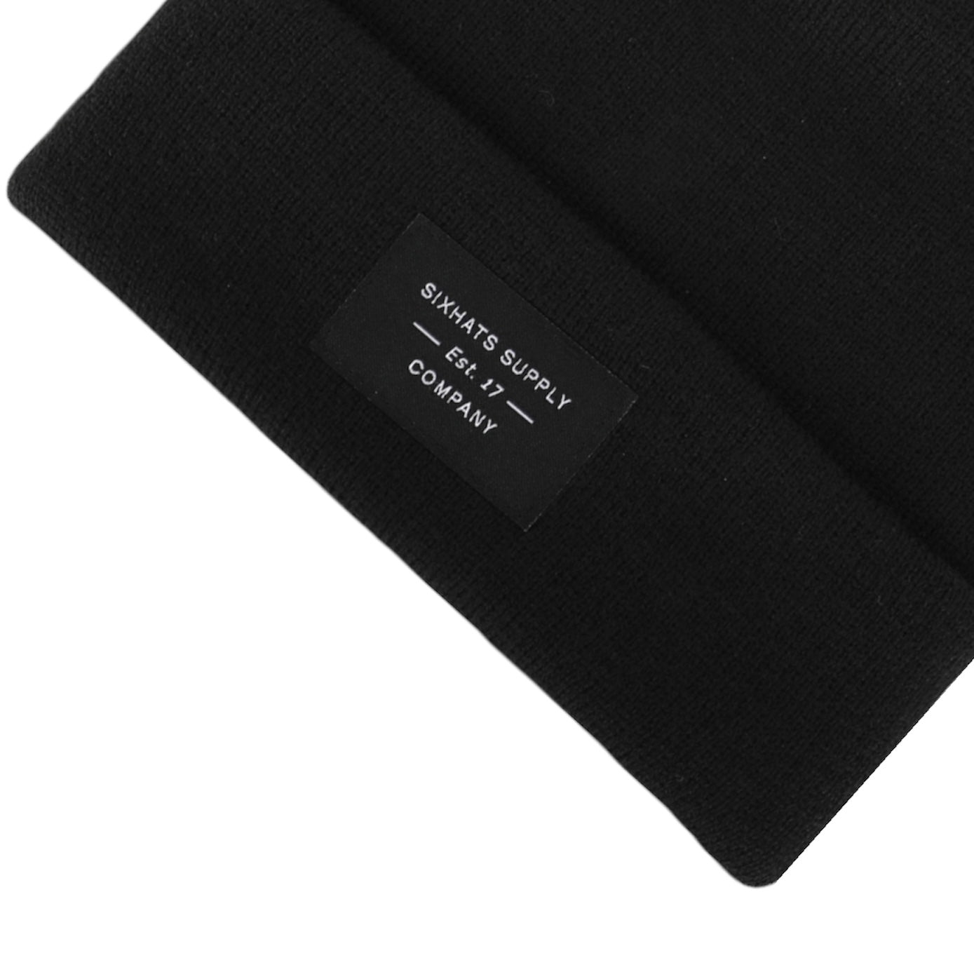 A soft black folding beanie with a woven label, showcasing its stylish design and versatility for various outfits.