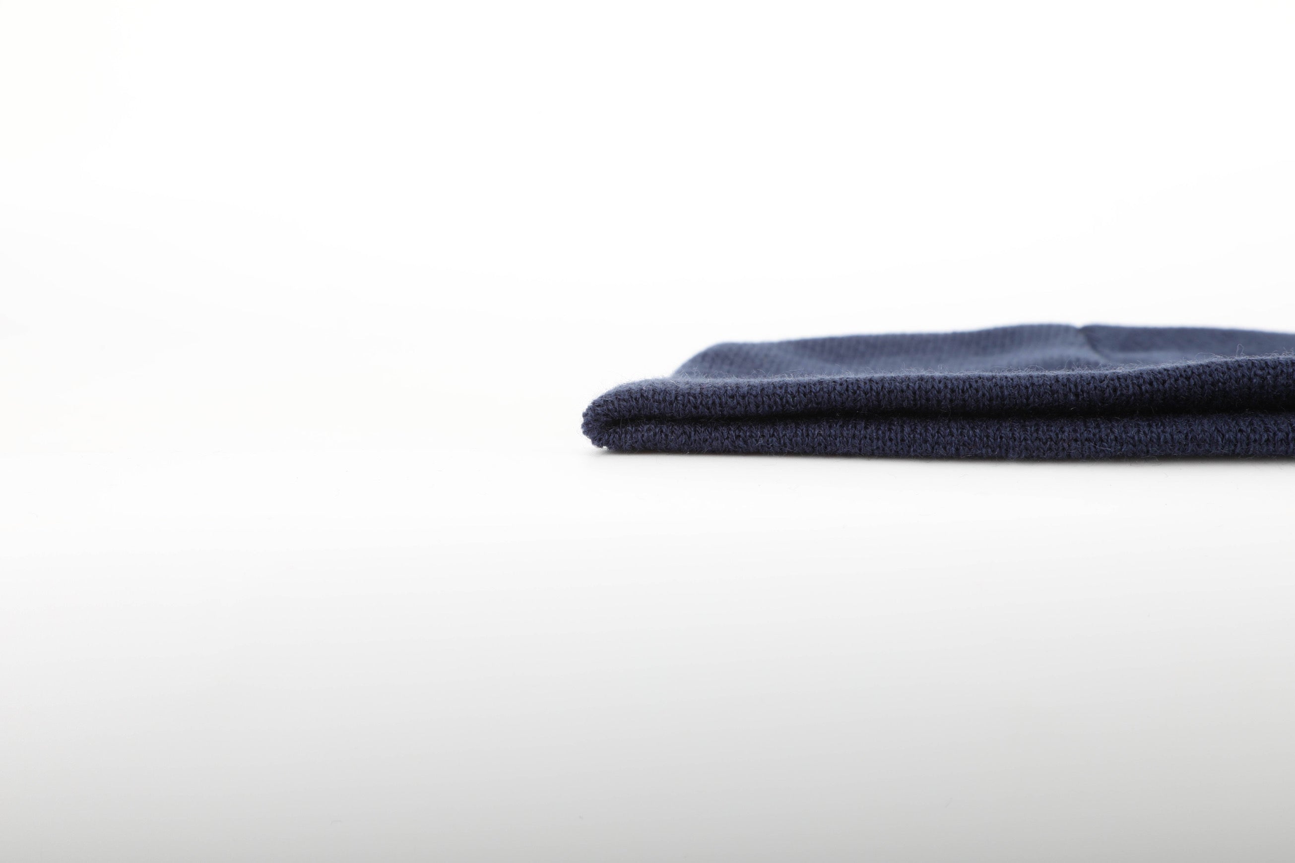 A stylish blue beanie with a suede arrow patch, perfect for winter sports and outdoor activities.