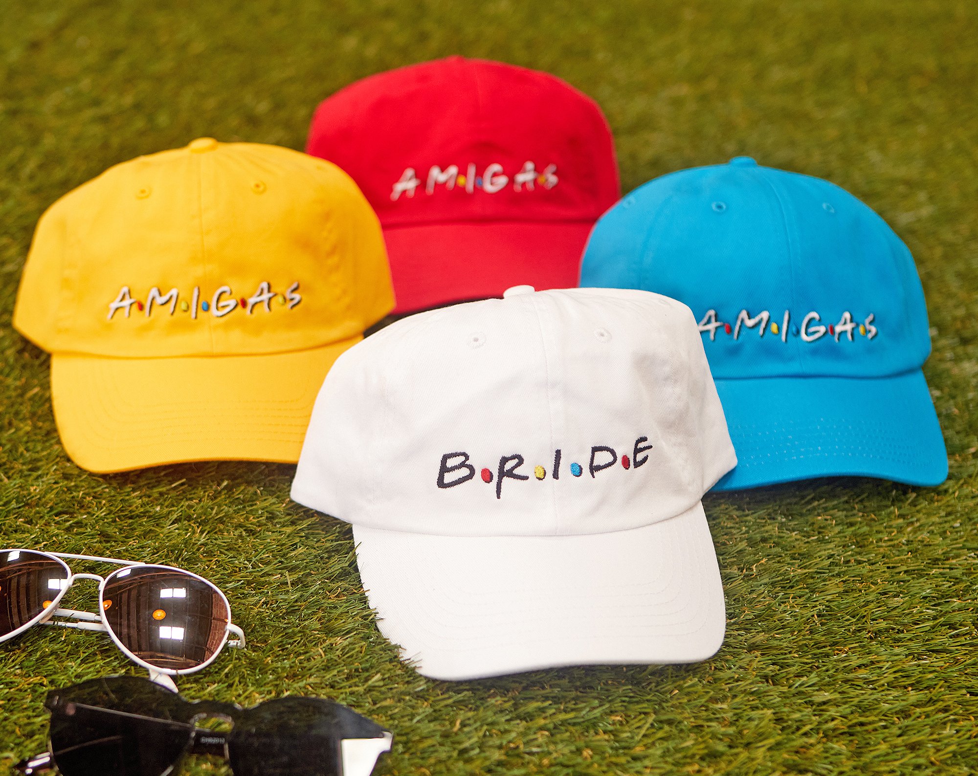 A stylish white hat labeled 'Bride' alongside colorful hats labeled 'Amigas', perfect for bachelorette parties.