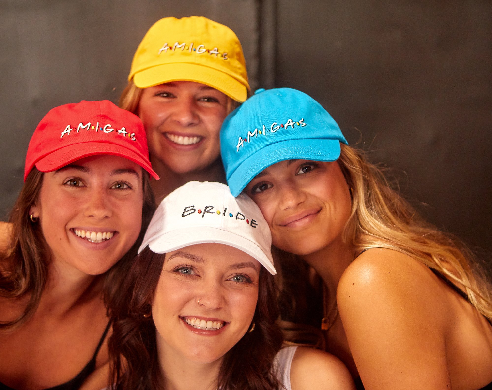 A stylish white hat labeled 'Bride' alongside colorful hats labeled 'Amigas', perfect for bachelorette parties.