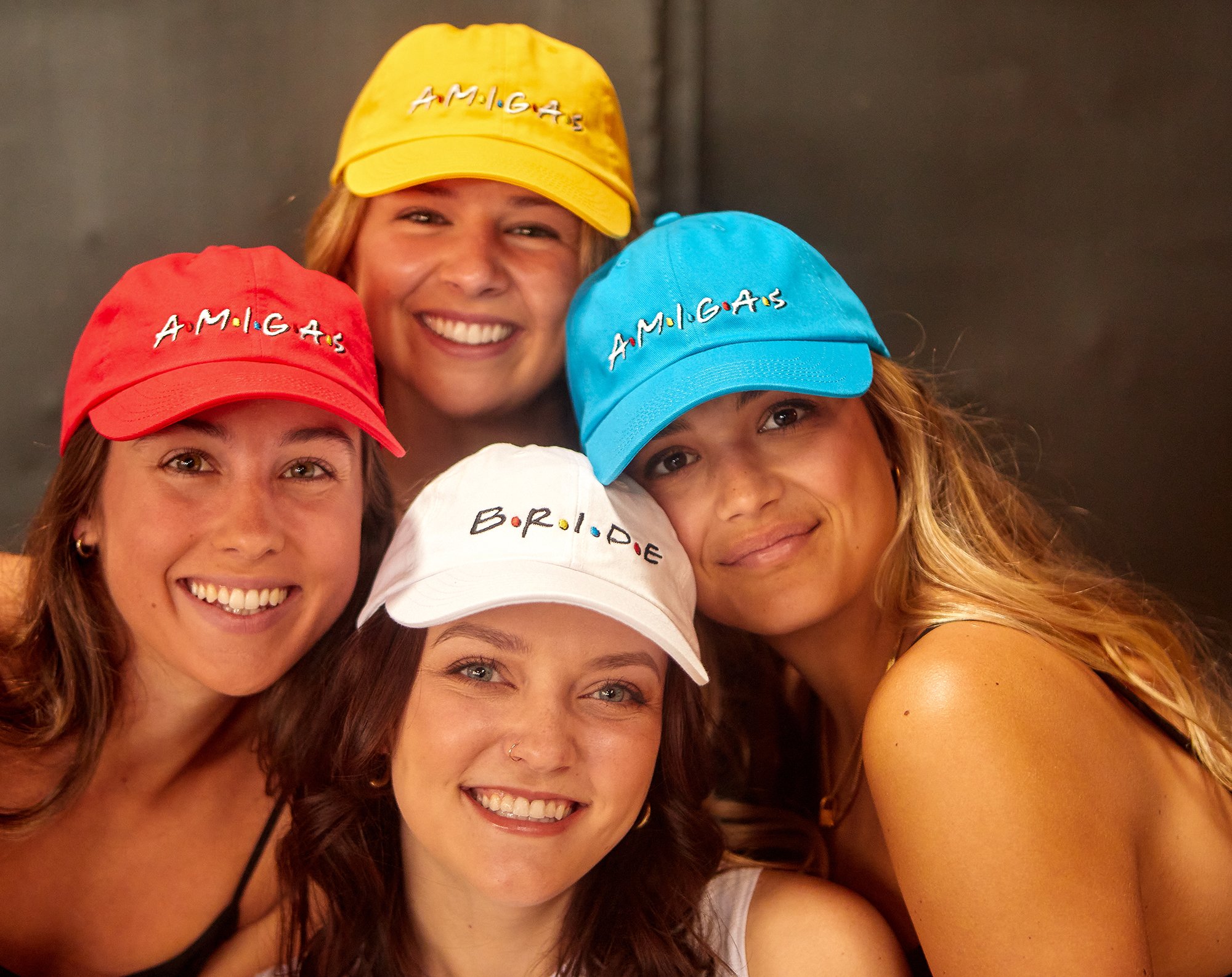 A stylish white hat labeled 'Bride' alongside colorful hats labeled 'Amigas', perfect for bachelorette parties.