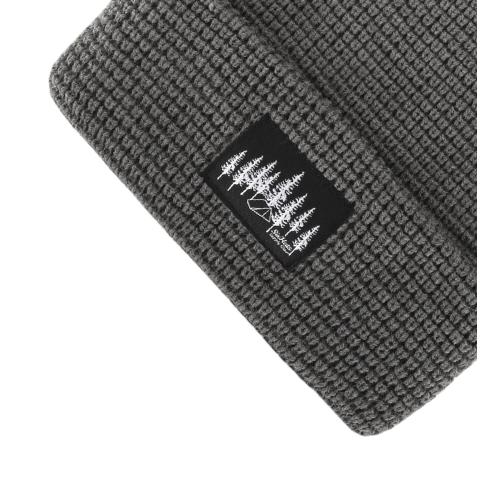 A stylish grey waffle knit beanie designed for warmth and comfort, featuring a woven Black Tree & Tent Explorer label.