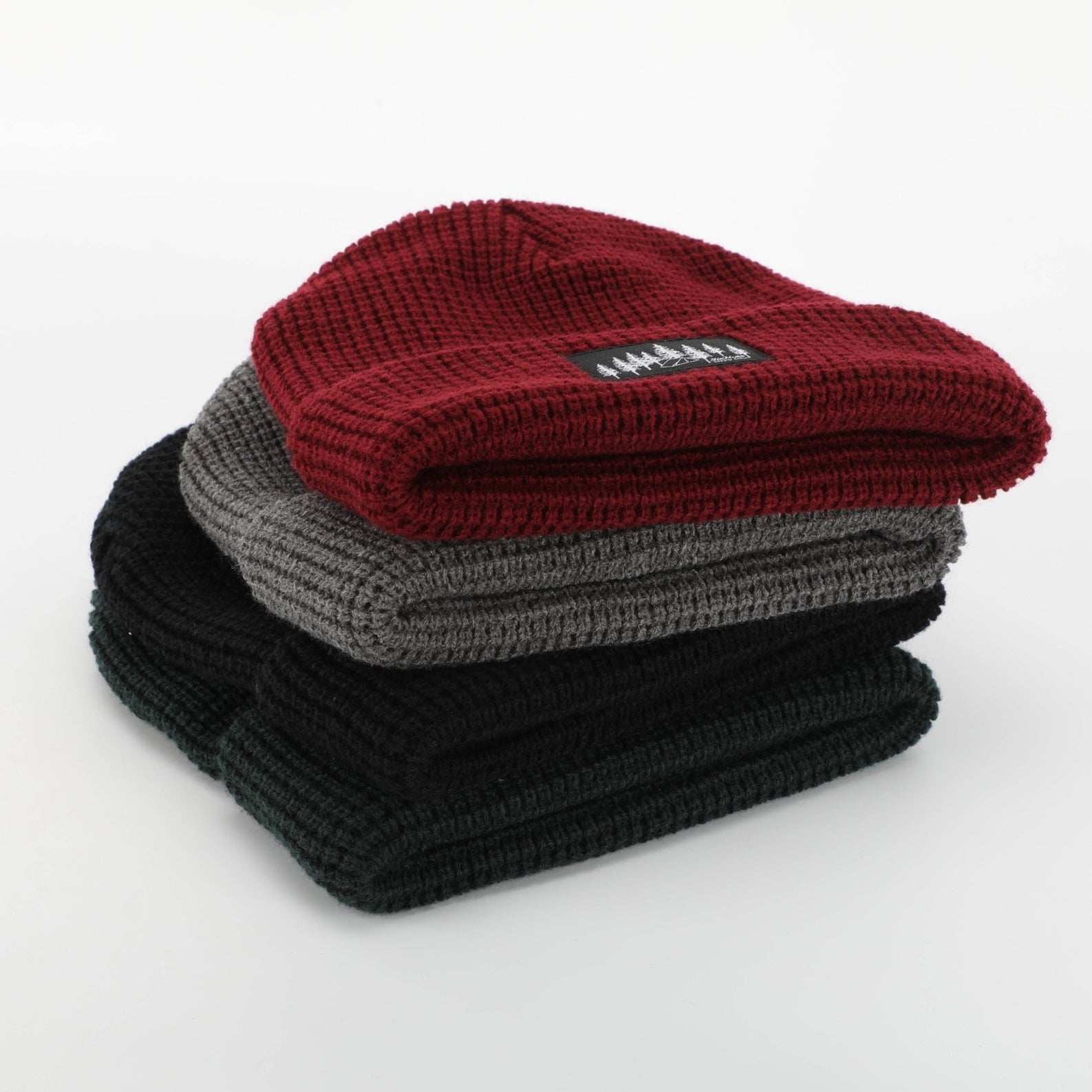 A stylish grey waffle knit beanie designed for warmth and comfort, featuring a woven Black Tree & Tent Explorer label.