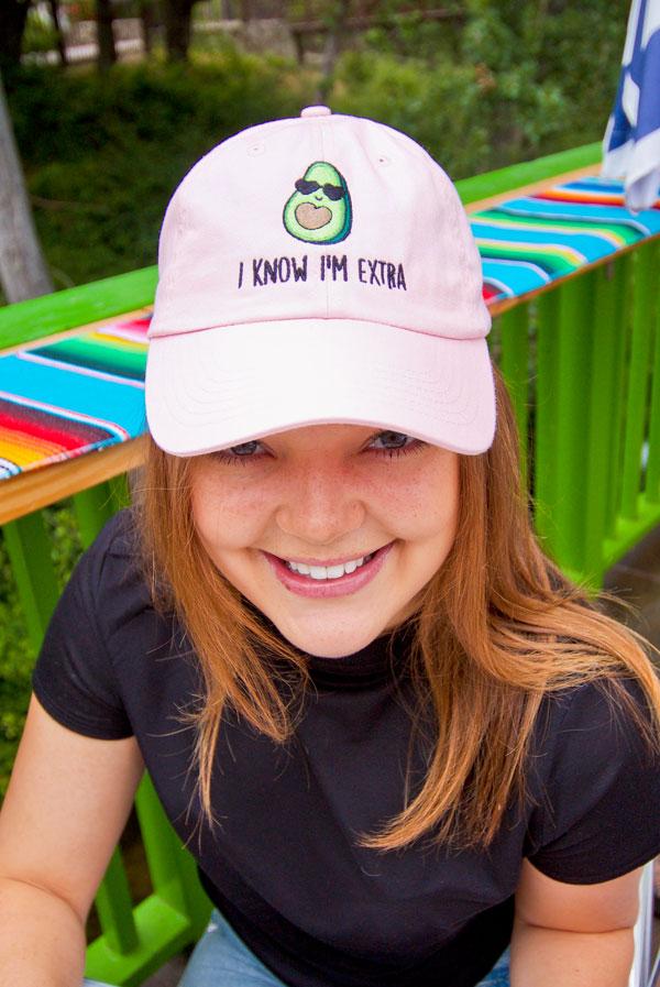 A collection of colorful fiesta avocado hats with fun phrases for weddings and celebrations, showcasing a white and soft pink design.