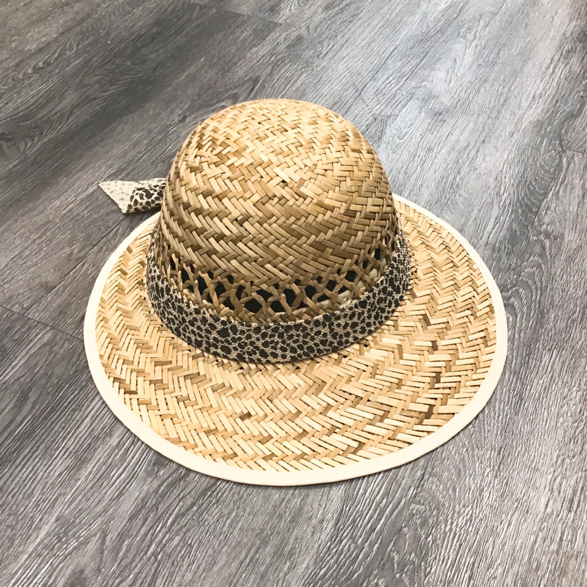 A stylish leopard print straw visor with a bow detail, perfect for sun protection.