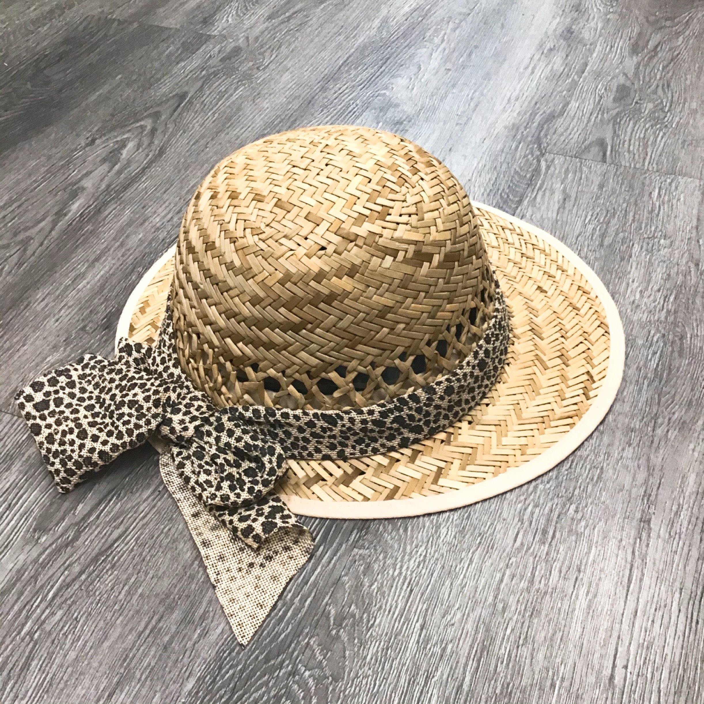 A stylish leopard print straw visor with a bow detail, perfect for sun protection.