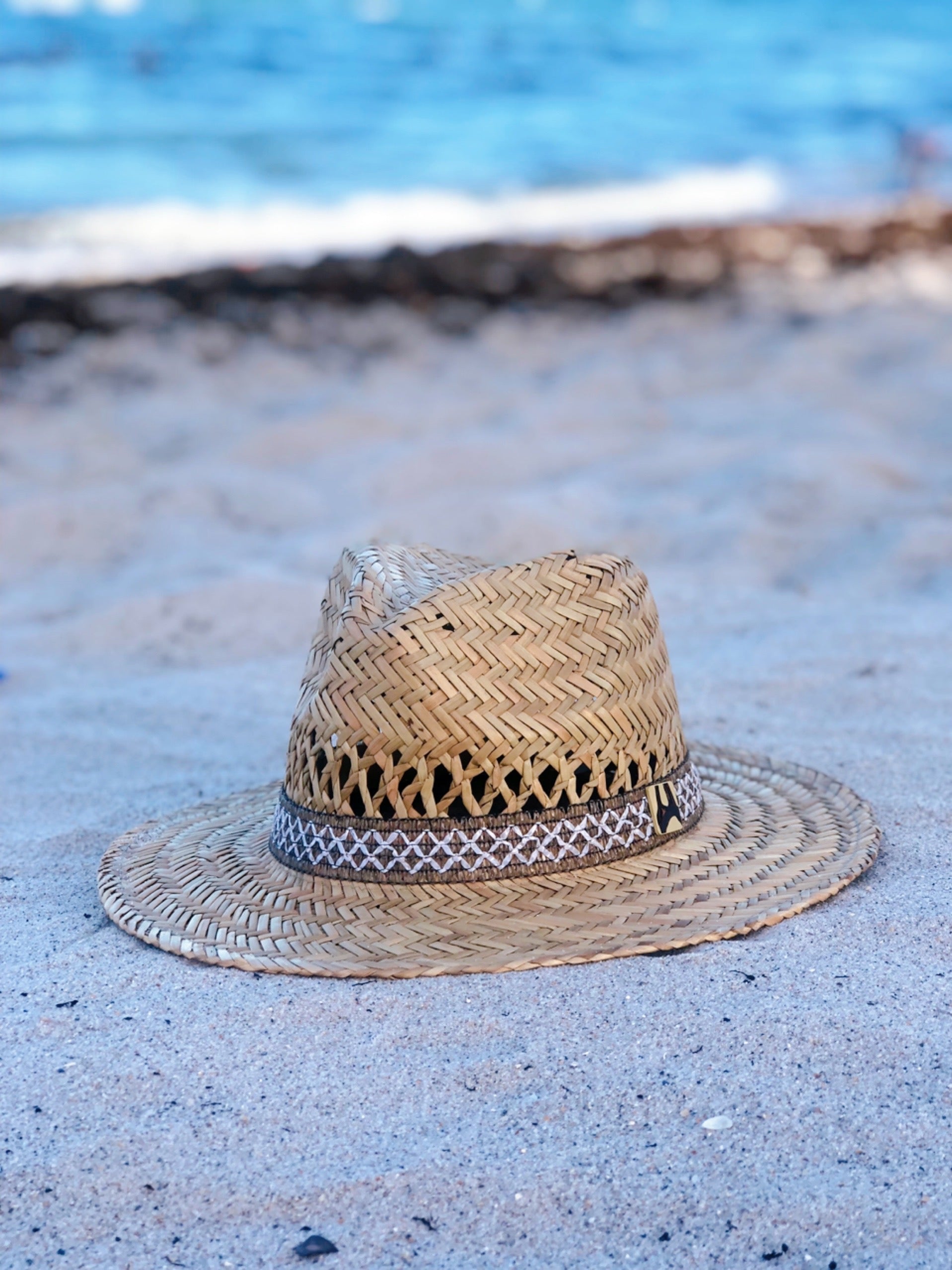 A stylish 'Meet me in the sand' Panama Hat made of rush straw with a braided thread trim and a 3.25-inch brim, perfect for sunny days.