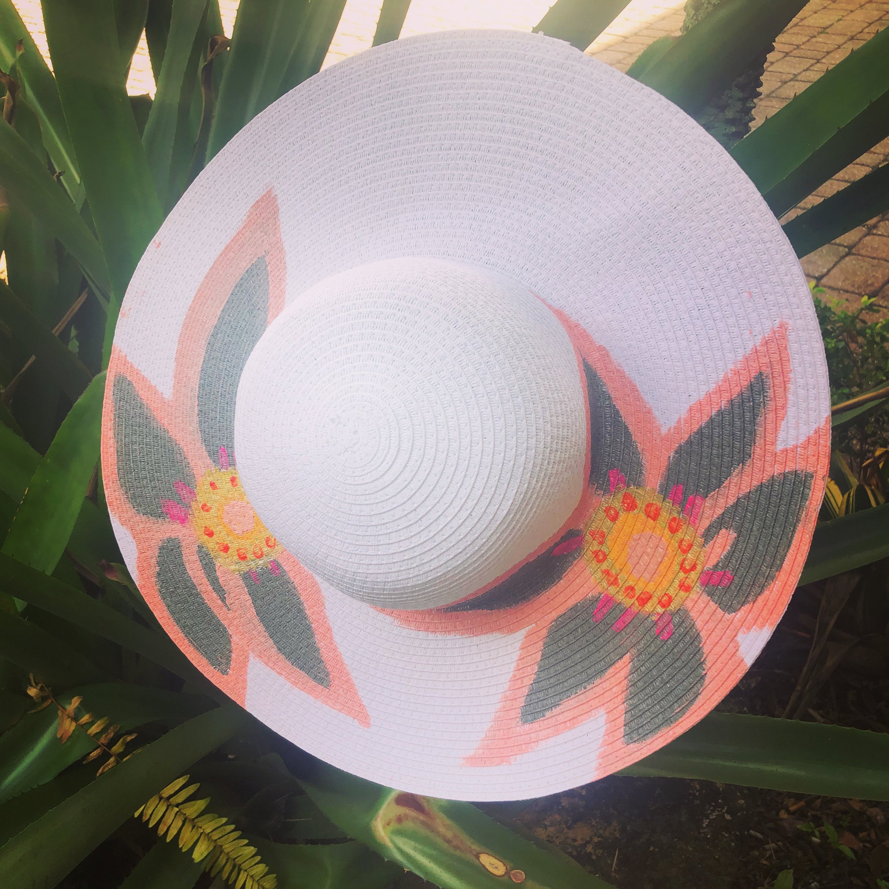 A vibrant pink handpainted sun hat adorned with floral designs, perfect for sunny days.