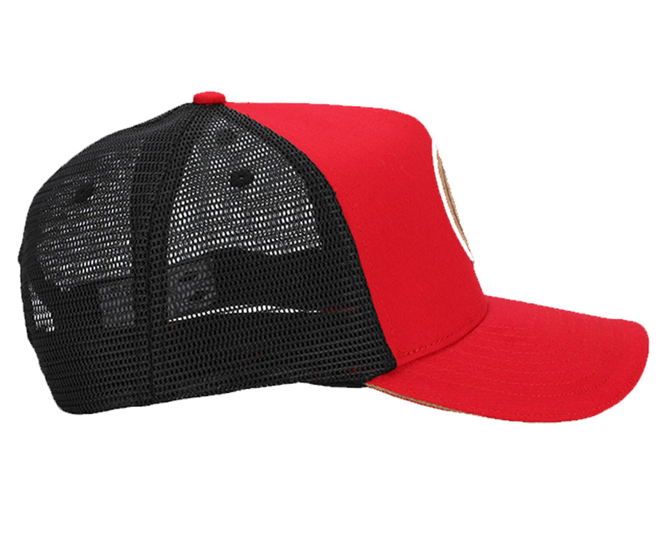 Red and black snapback hat with cork brim and mesh back, featuring a round recycled cork patch.