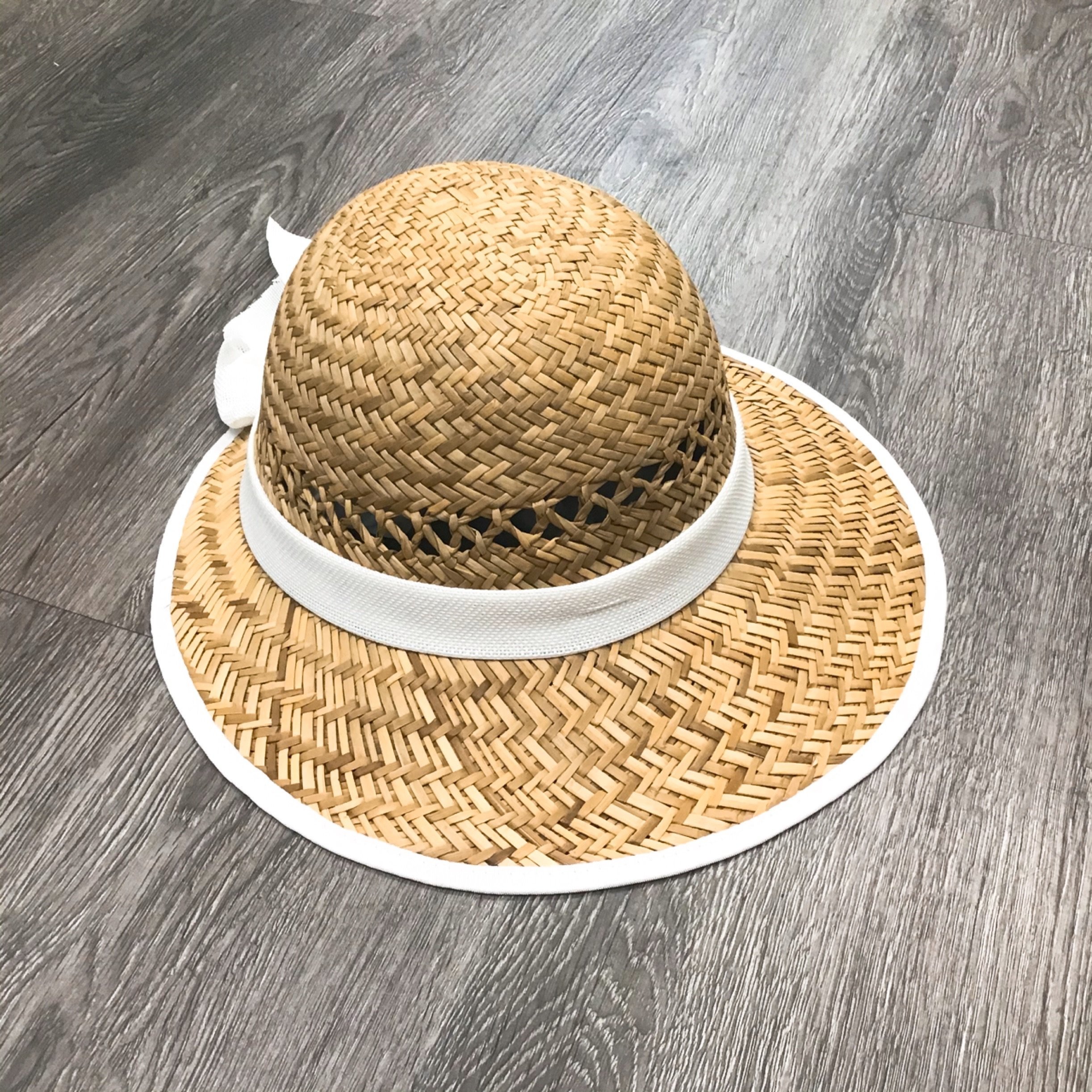 Solid white straw visor with a stylish bow accent, perfect for sun protection.