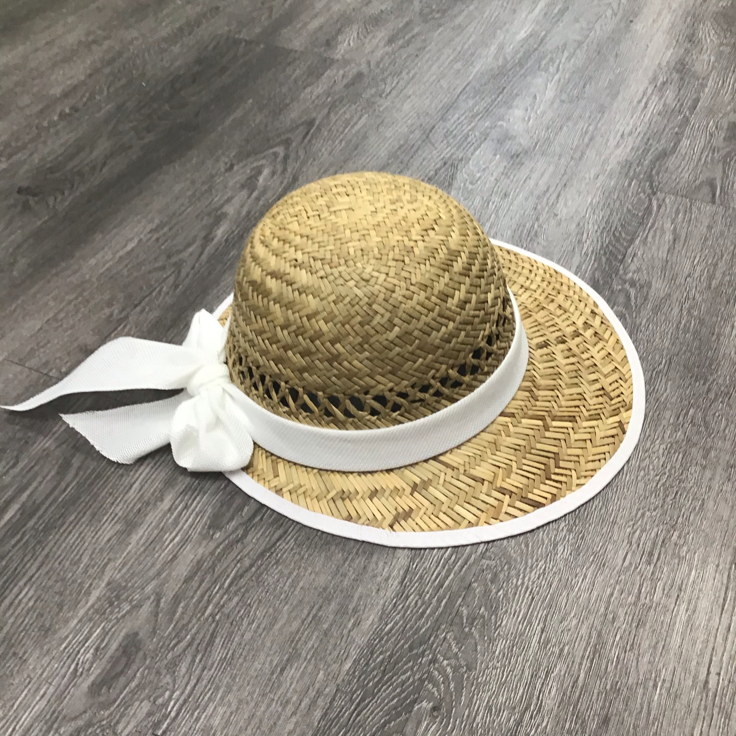 Solid white straw visor with a stylish bow accent, perfect for sun protection.