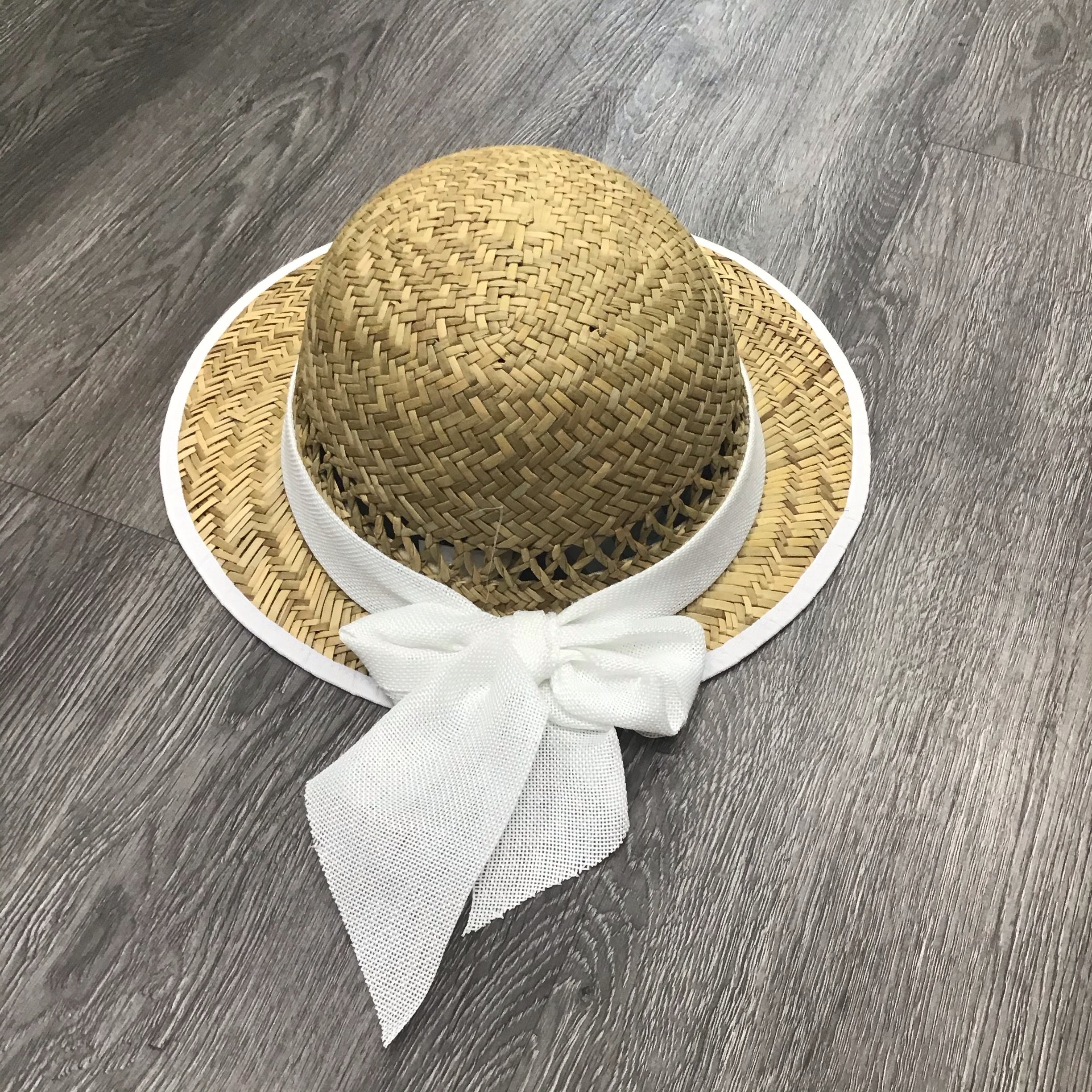 Solid white straw visor with a stylish bow accent, perfect for sun protection.