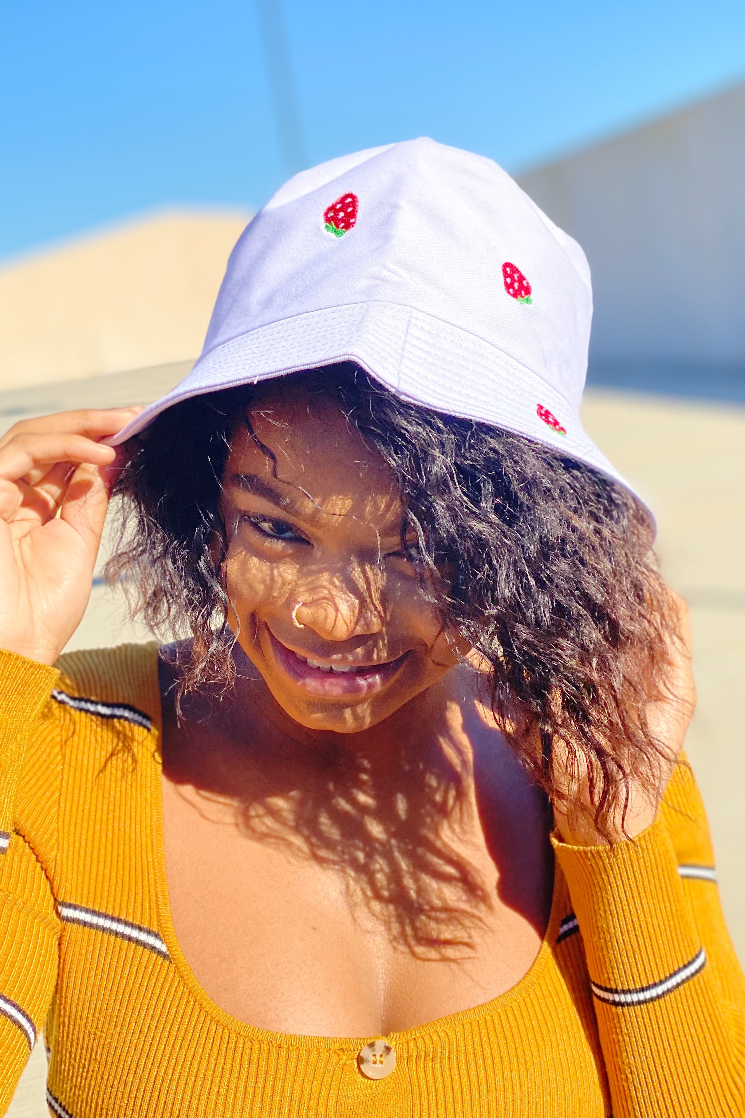 A colorful bucket hat with embroidered fruit patterns, made of high-quality cotton, perfect for sunny days.