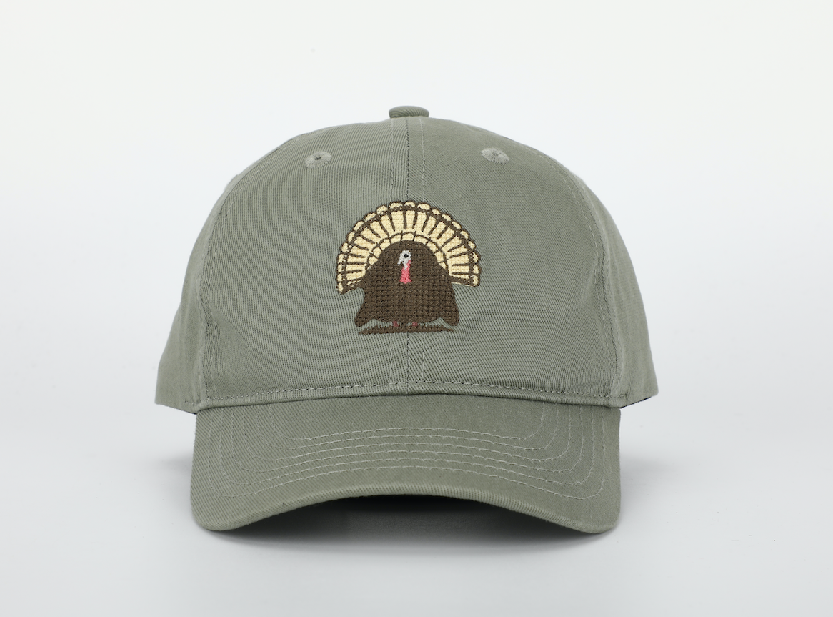 A colorful Turkey Hat designed for children, featuring a cognac leather adjustable strap and brass embossed buckle, adorned with needlepoint embroidery.