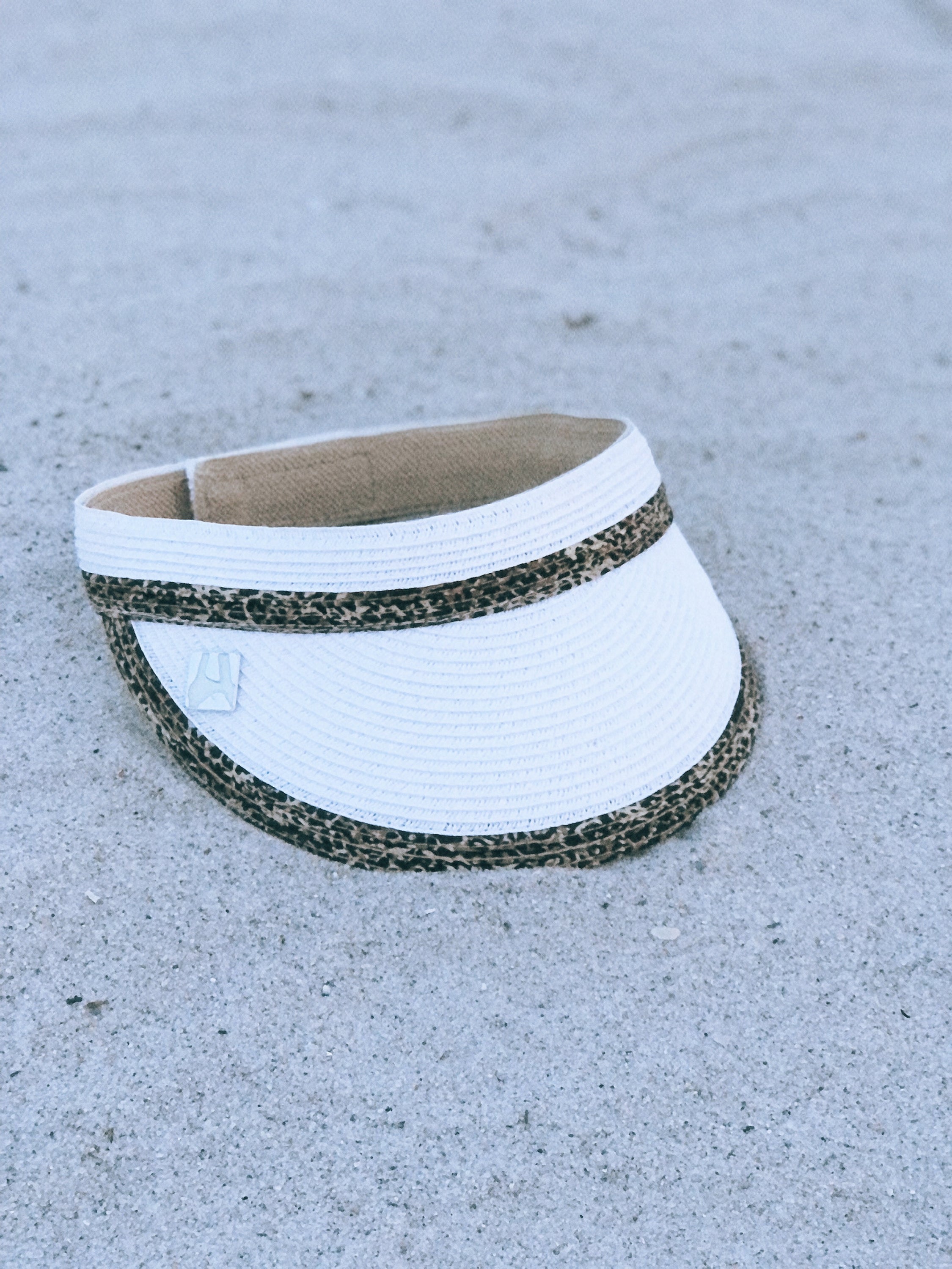 A stylish white animal print visor hat made from toyo braid material with a 3.5-inch brim and adjustable velcro closure.