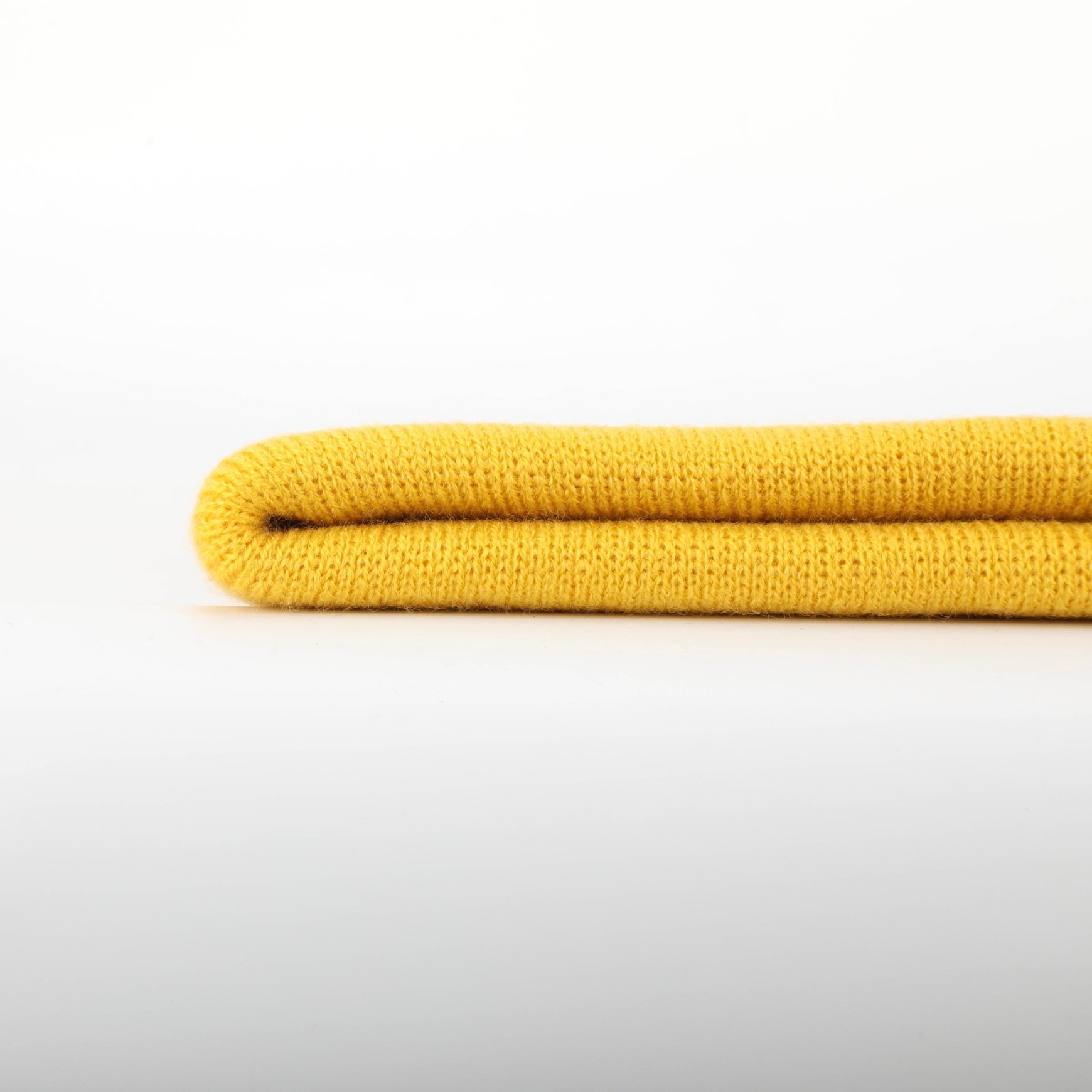 A vibrant yellow folding beanie made from soft, moisture-wicking material, perfect for stylish warmth in cold weather.