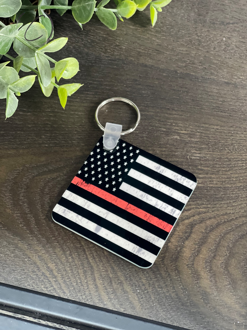 A durable Thin Red Line Keychain featuring a unique design on both sides, measuring 2.25 inches by 2.25 inches, made from high-quality plastic.