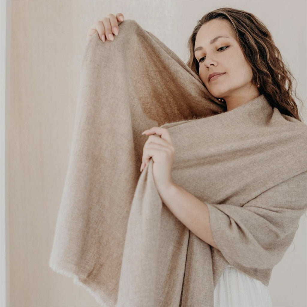 A luxurious beige handloom cashmere scarf, showcasing its soft texture and oversized design, perfect for layering in cold weather.