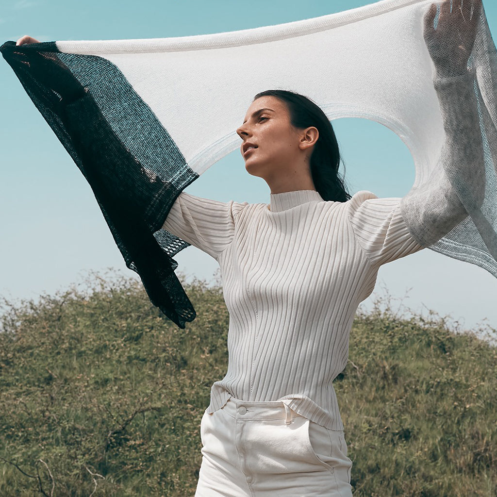 A luxurious Color Block Alpaca Wrap Scarf featuring a delicate eyelet design, showcasing shades of black, gray, and snow, perfect for layering.