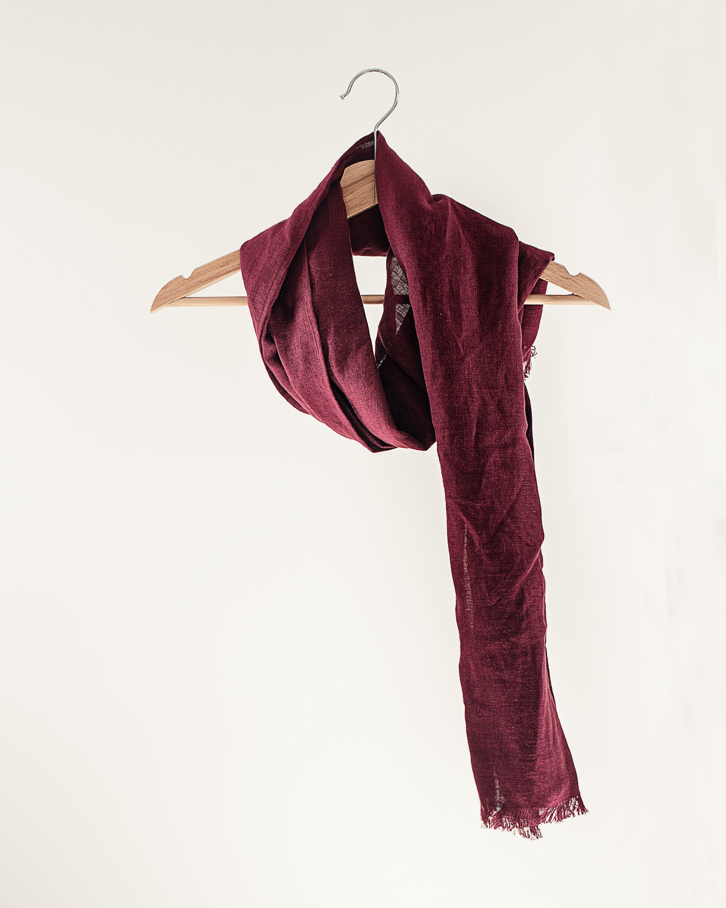 A stylish Dark Plum linen scarf made from 100% stonewashed linen, showcasing its soft texture and vibrant color.