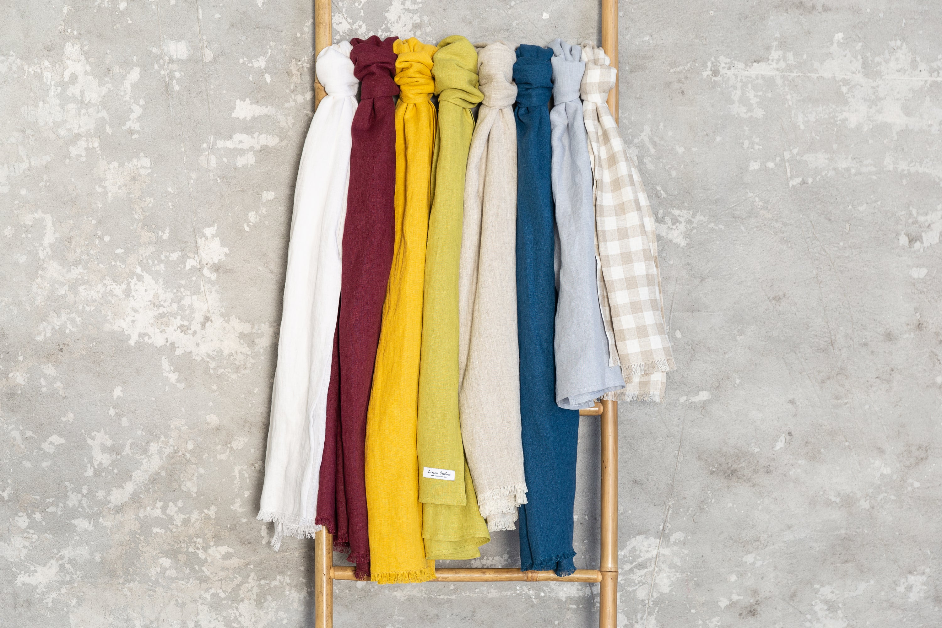 A vibrant collection of lightweight linen scarves in various colors, showcasing their soft texture and stylish design.