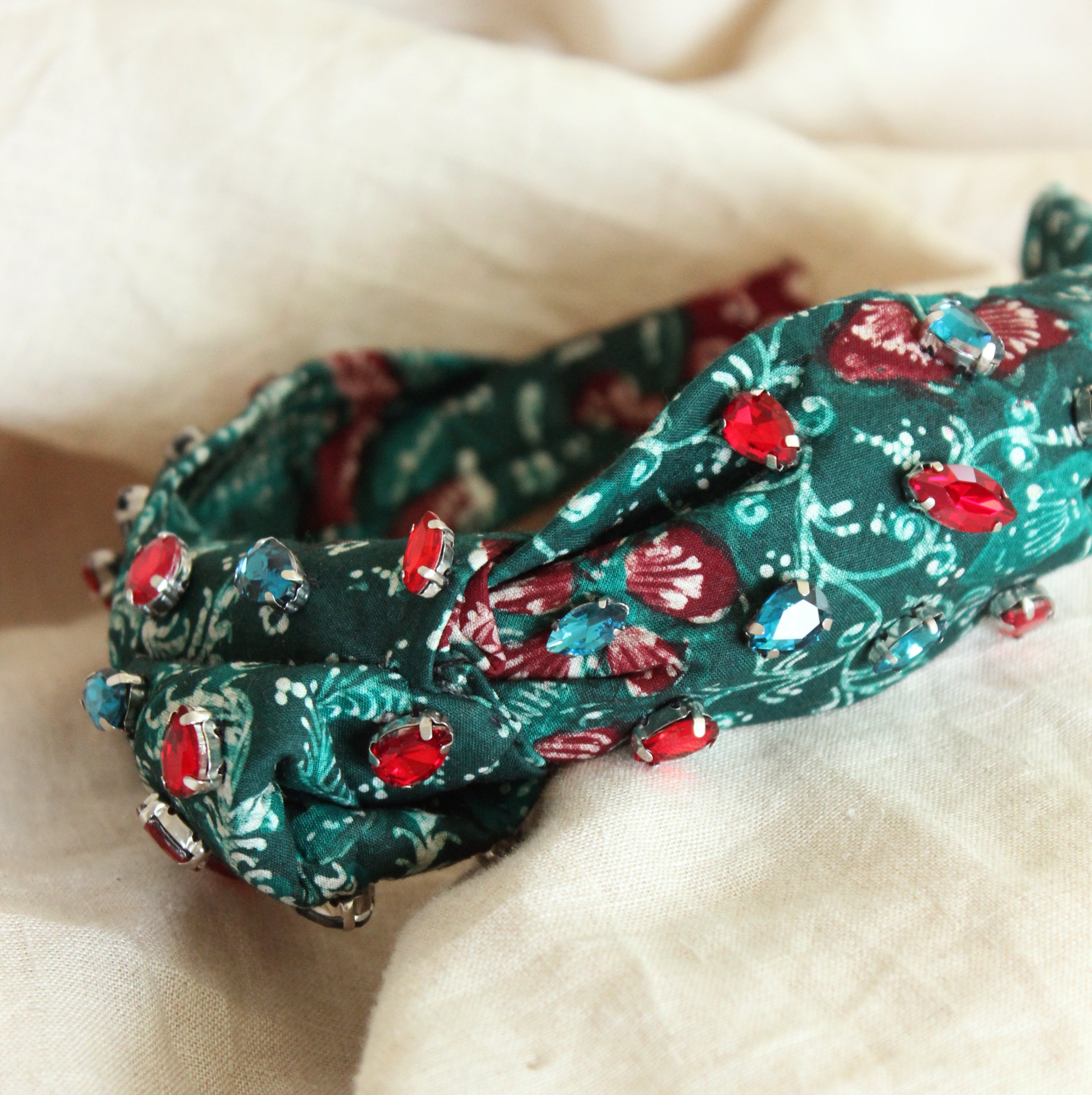 MERAK Peacock Headband featuring turquoise and red batik fabric with shimmering crystals, showcasing intricate designs.