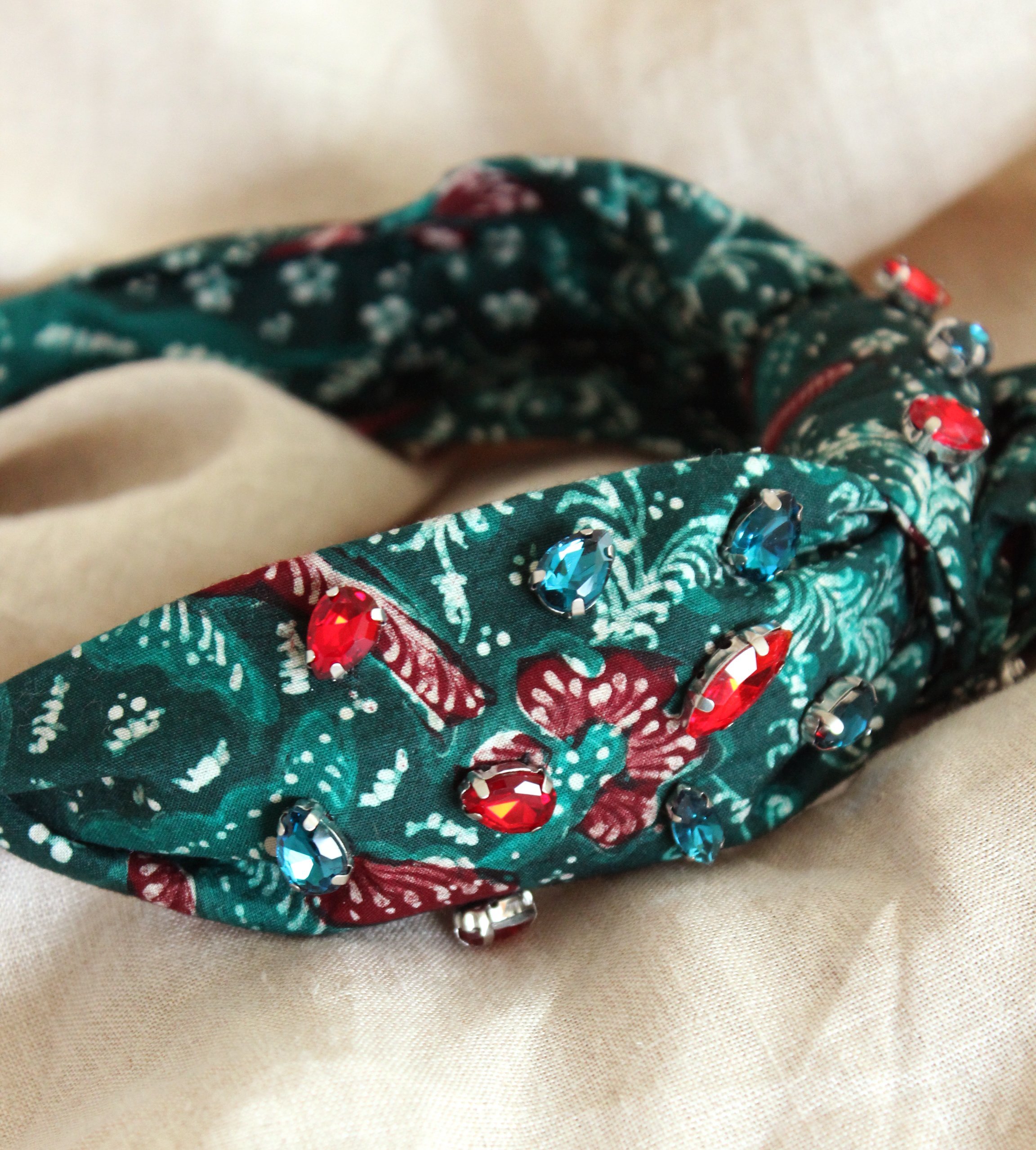 MERAK Peacock Headband featuring turquoise and red batik fabric with shimmering crystals, showcasing intricate designs.