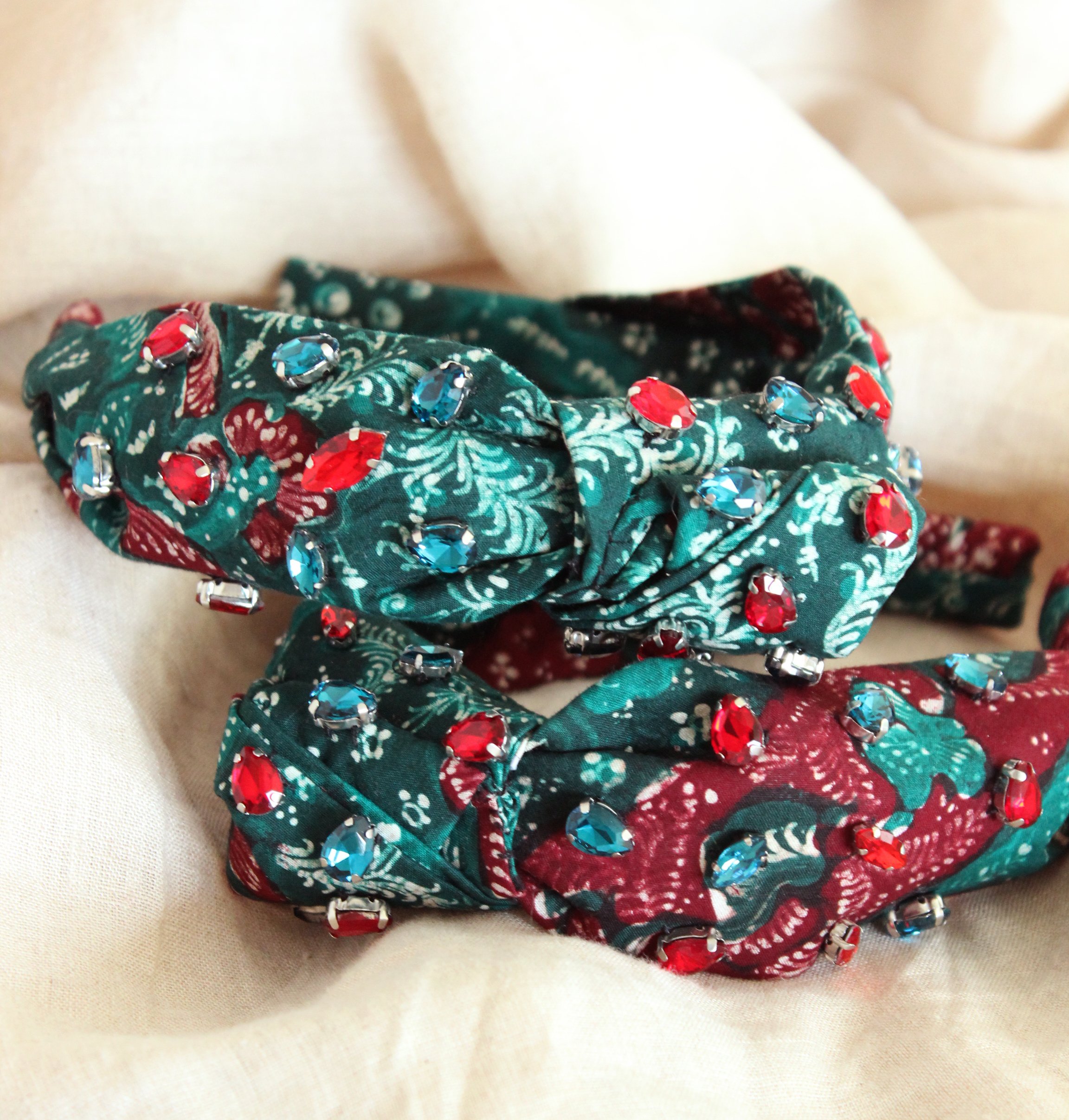 MERAK Peacock Headband featuring turquoise and red batik fabric with shimmering crystals, showcasing intricate designs.