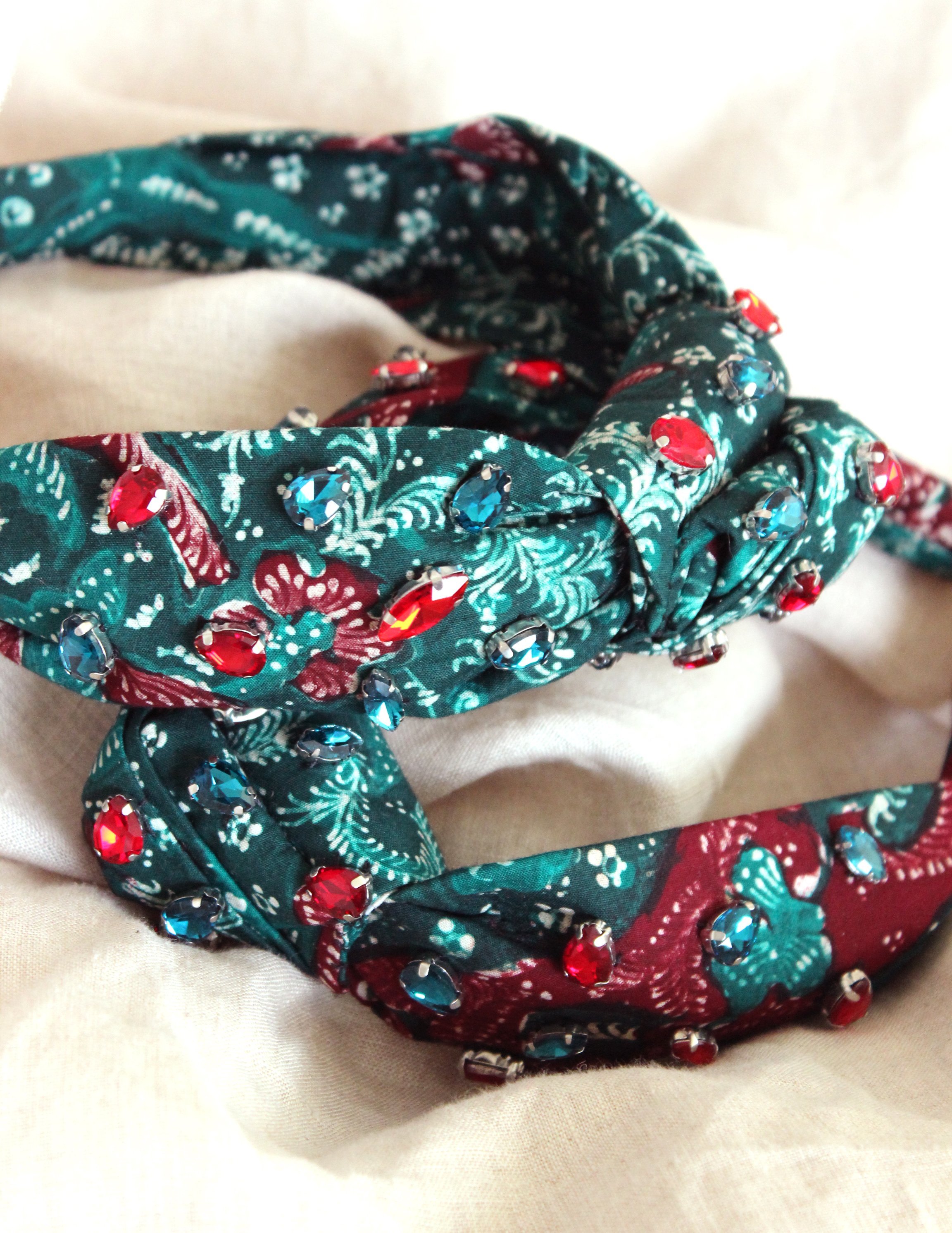 MERAK Peacock Headband featuring turquoise and red batik fabric with shimmering crystals, showcasing intricate designs.