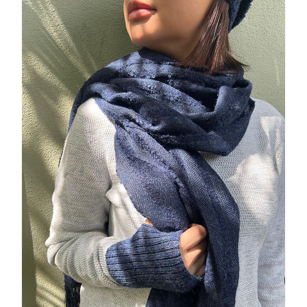 A luxurious navy blue loop knit alpaca scarf with fluffy fringe edges, showcasing its soft texture and unique design.