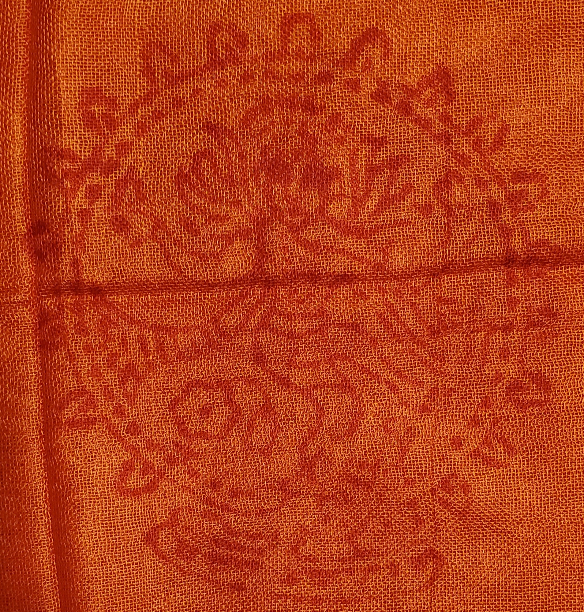 A luxurious red-orange scarf featuring intricate Sanskrit writing and Om symbols, made from 100% cotton.