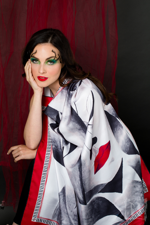 A luxurious silk scarf featuring a self-portrait design with vibrant red lips and a large closed eye, symbolizing contemplation, elegantly displayed in a gift box.