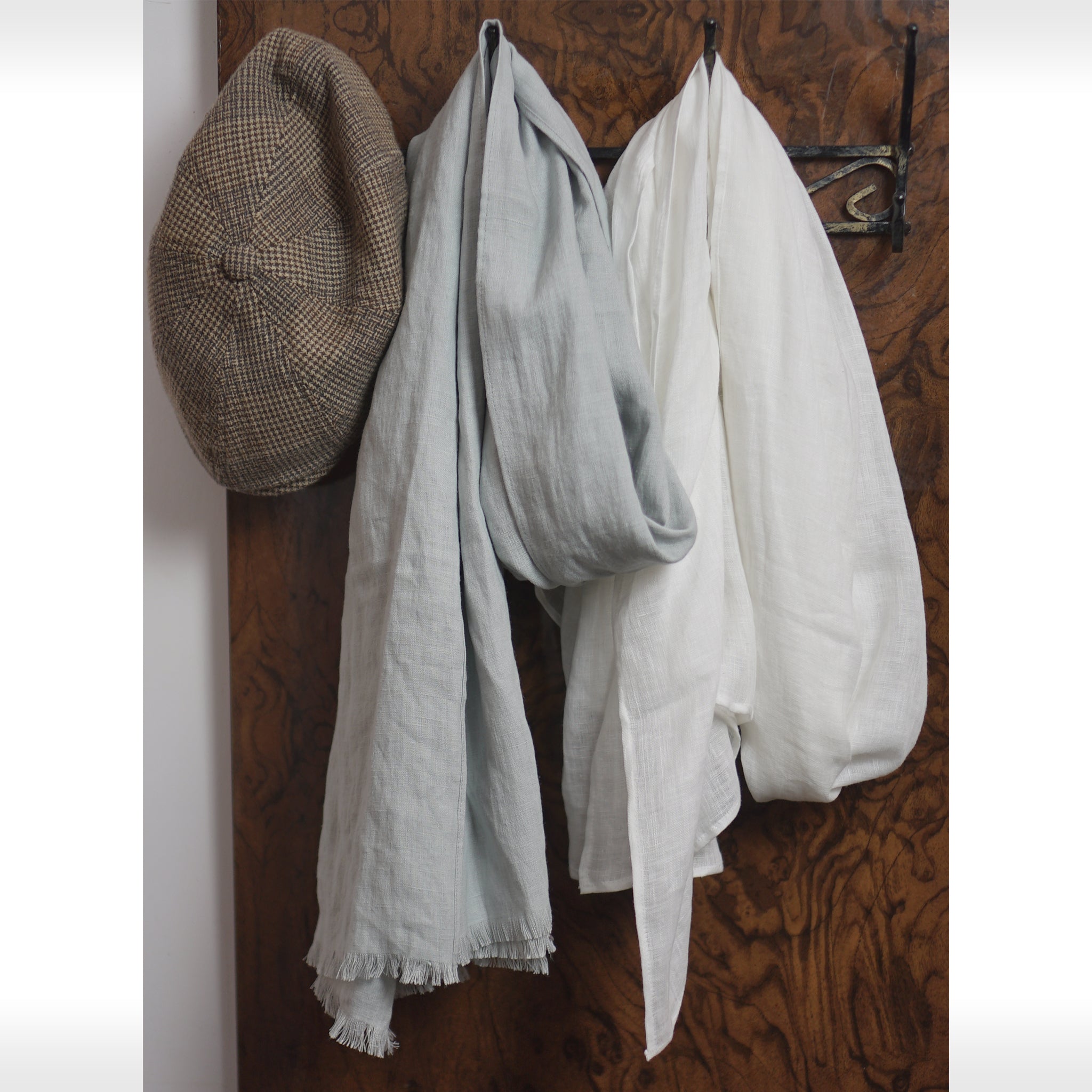 A soft and lightweight Snow White linen scarf, elegantly draped, showcasing its semi-sheer texture and stylish design.