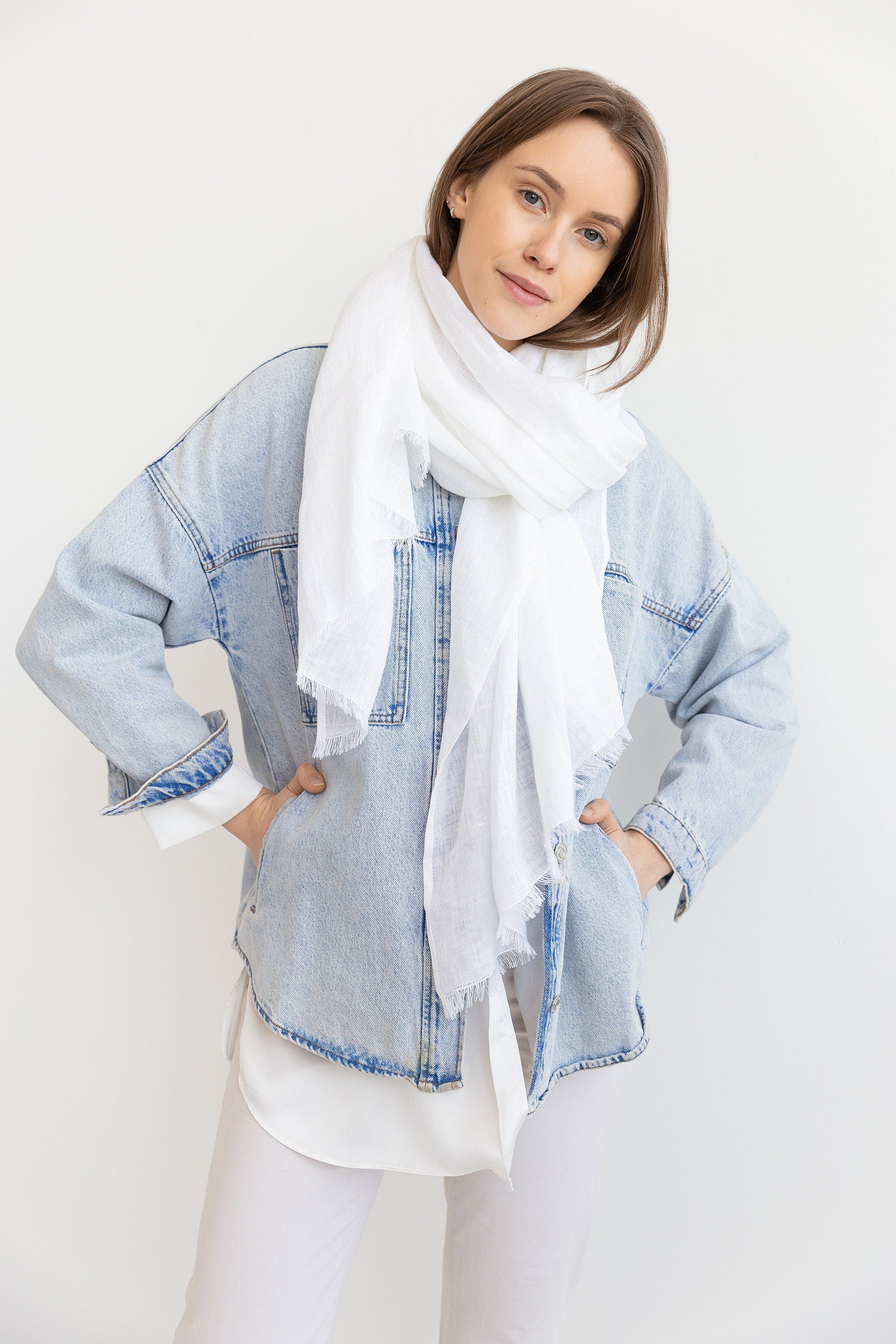 A stylish white linen lightweight scarf draped elegantly, showcasing its soft texture and tassel details.