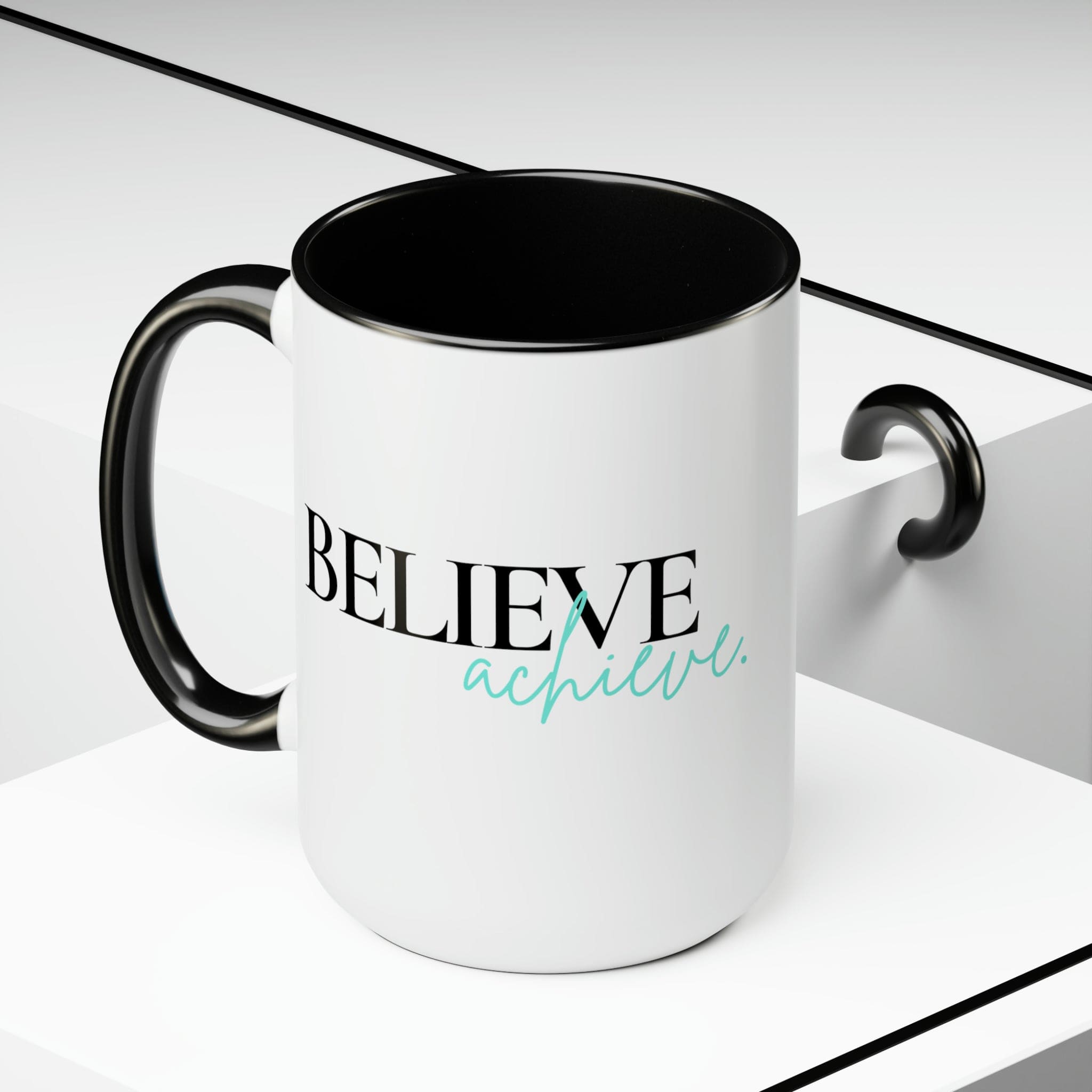 Black ceramic coffee mug with colored interior and handle, featuring the inspirational phrase 'Believe and Achieve'.