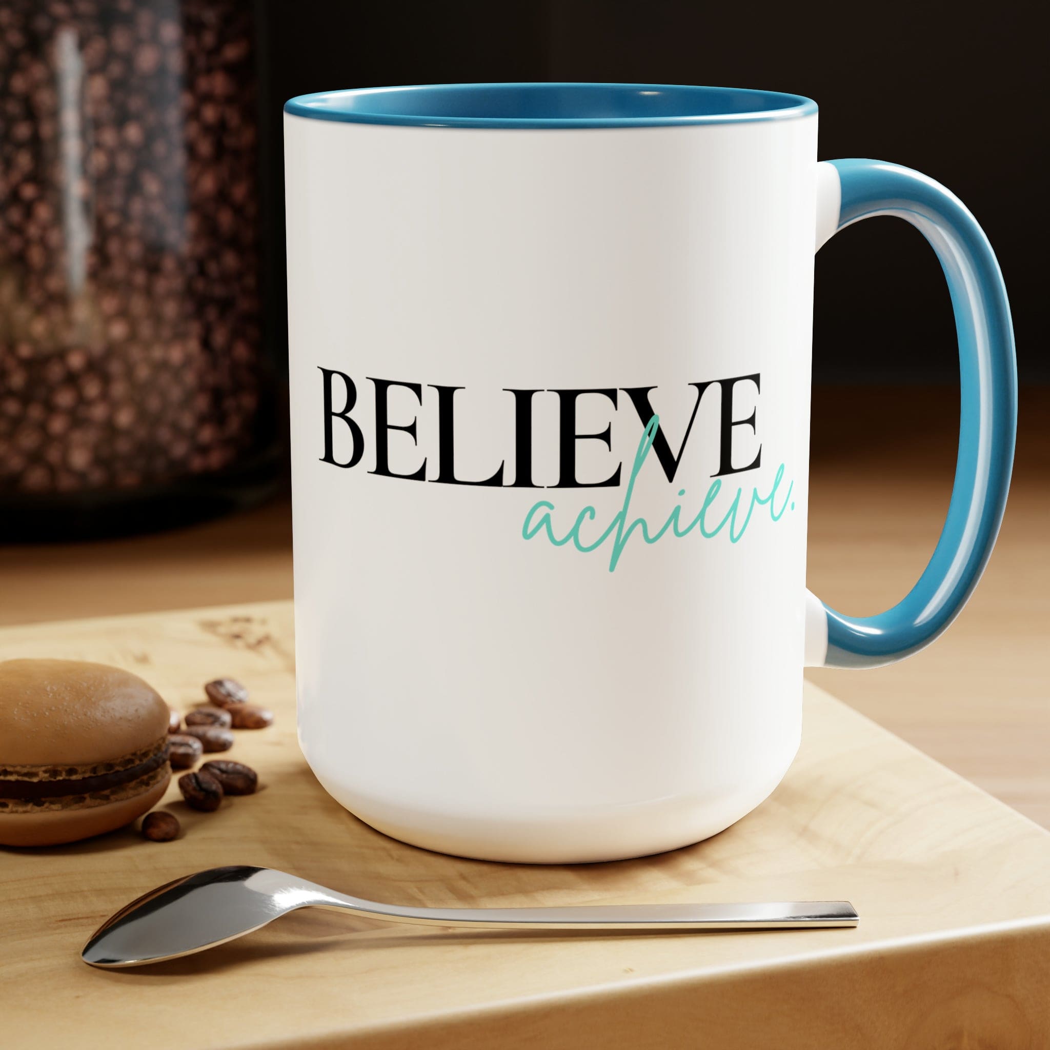 Black ceramic coffee mug with colored interior and handle, featuring the inspirational phrase 'Believe and Achieve'.