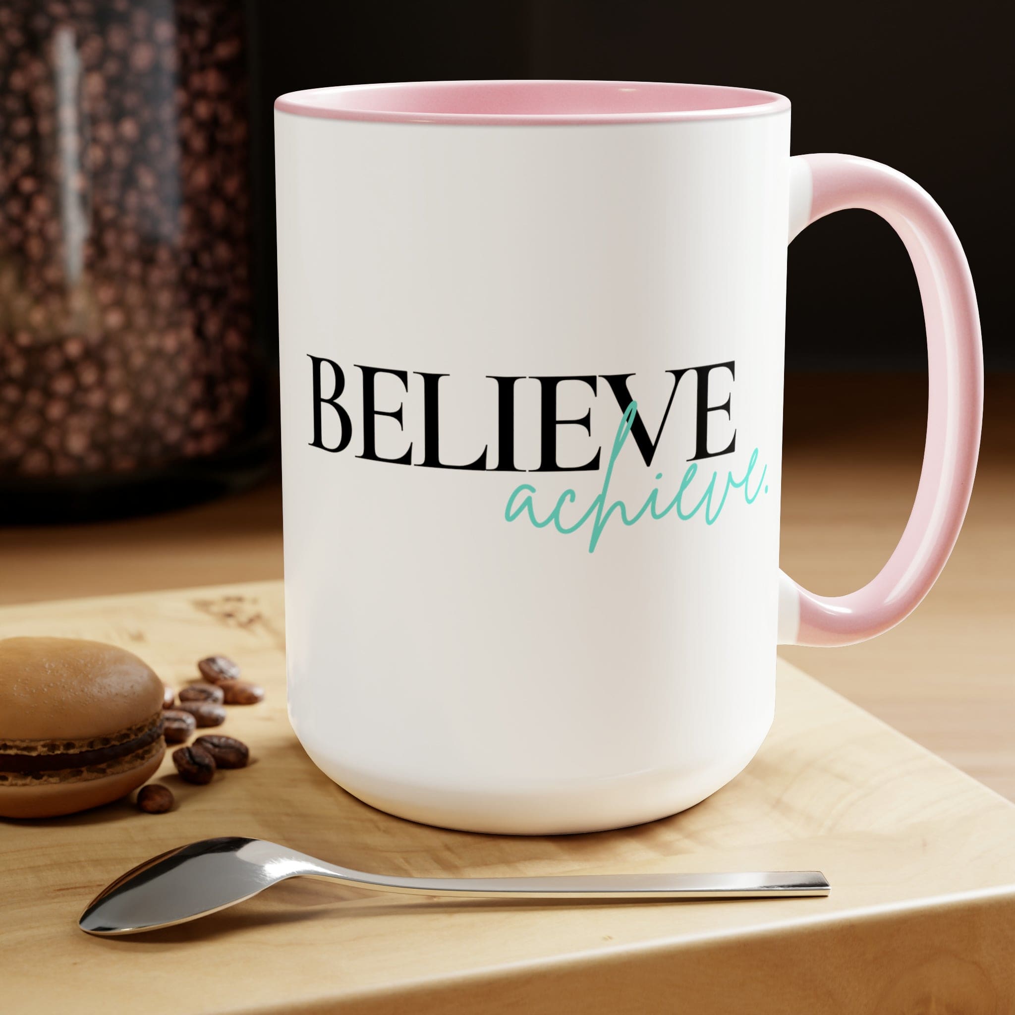 Black ceramic coffee mug with colored interior and handle, featuring the inspirational phrase 'Believe and Achieve'.