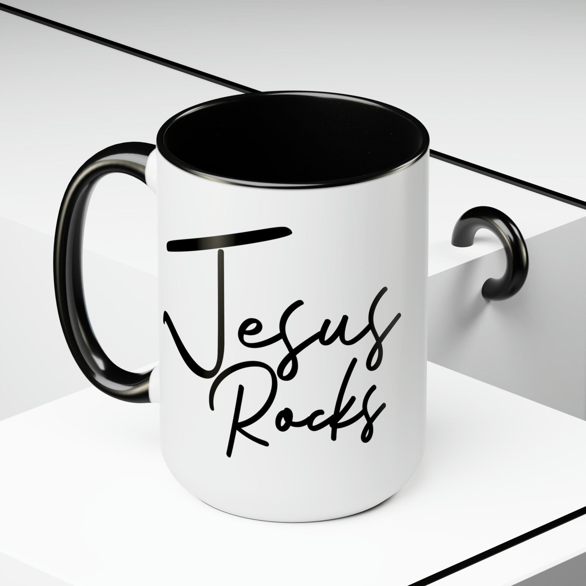 Black ceramic coffee mug with 'Jesus Rocks' text, featuring a colored interior and handle, perfect for hot and cold beverages.