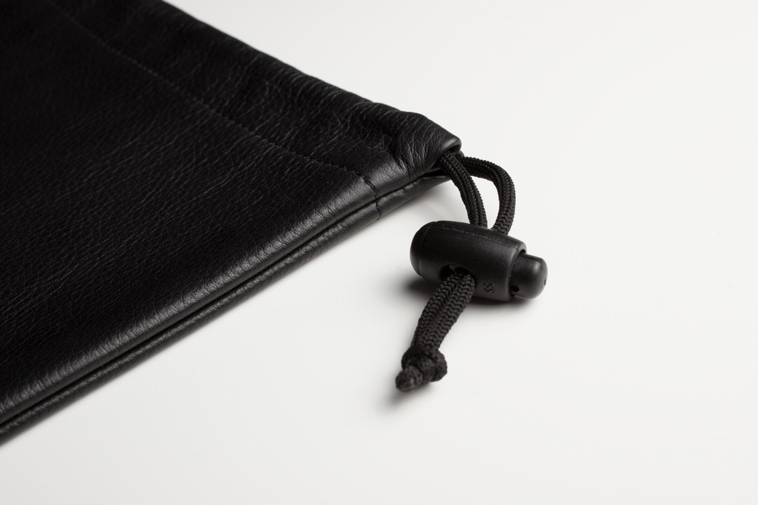 A stylish cowhide leather accessory pouch with adjustable pull string closure, featuring a suede lined interior.